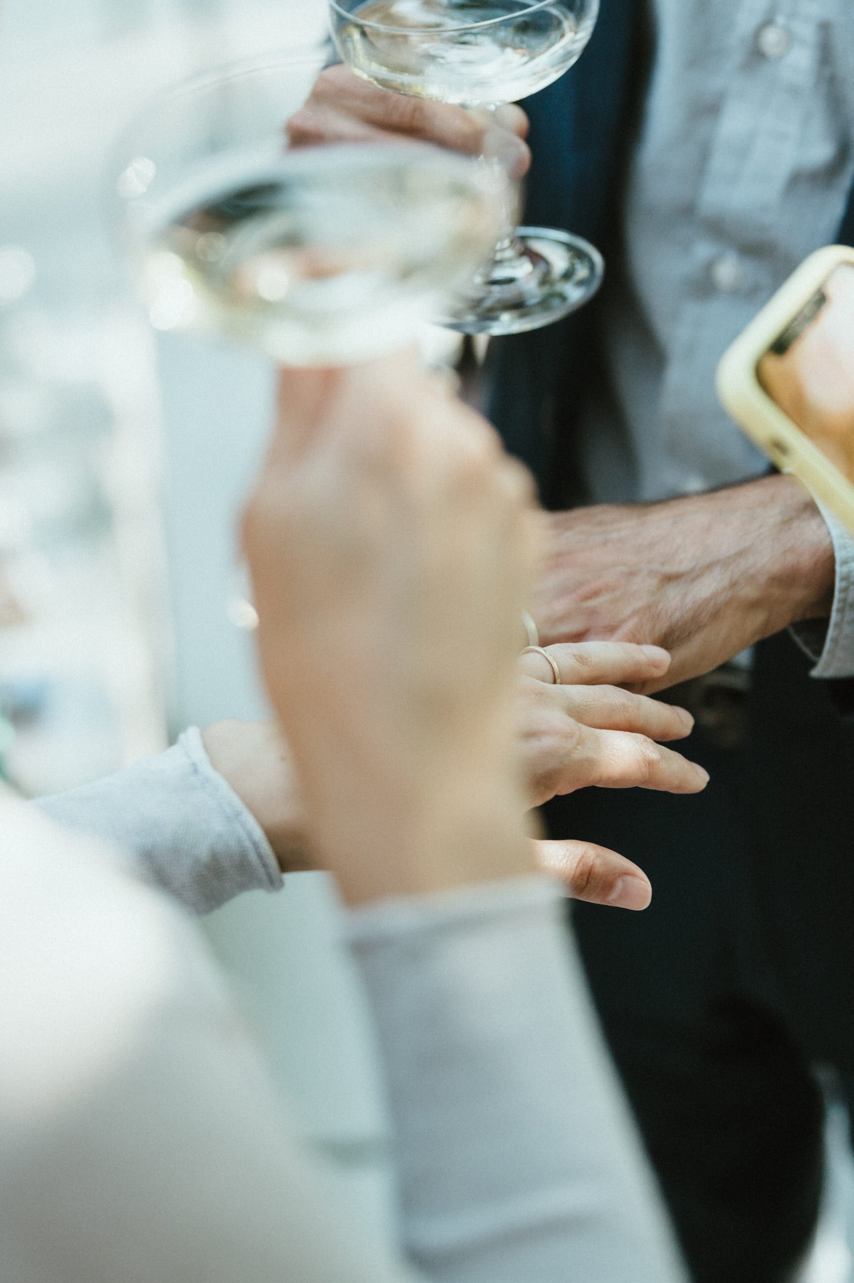 bride and groom hands with wedding rings side by side holding wine glasses