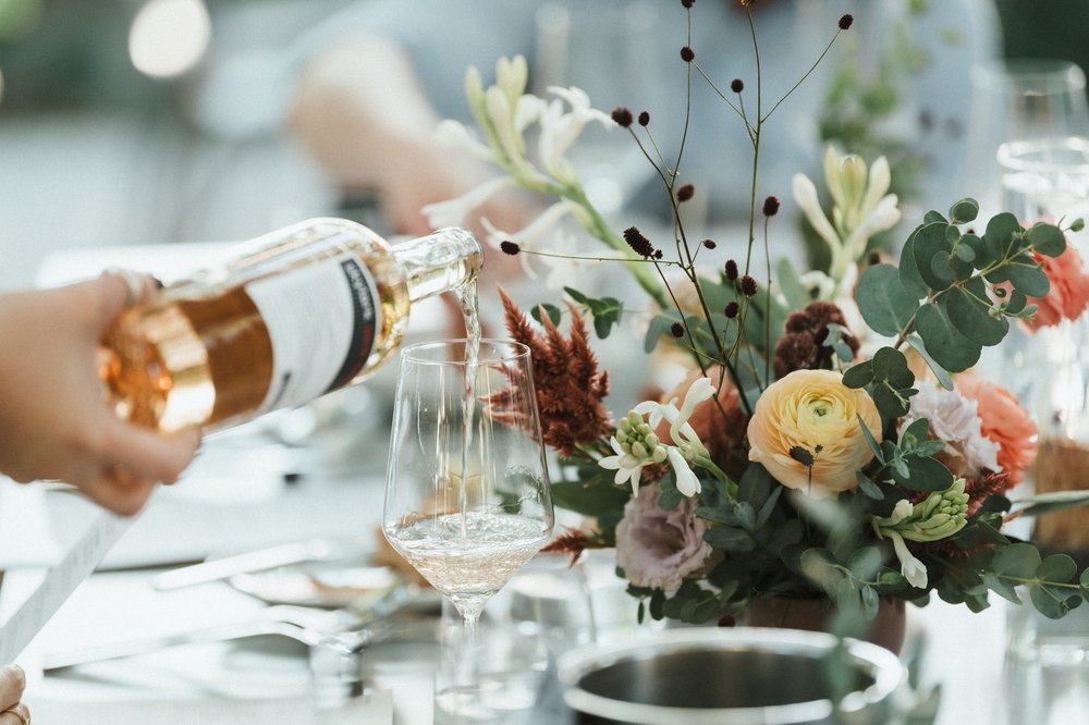 colorful florals and wine being poured at post wedding dinner