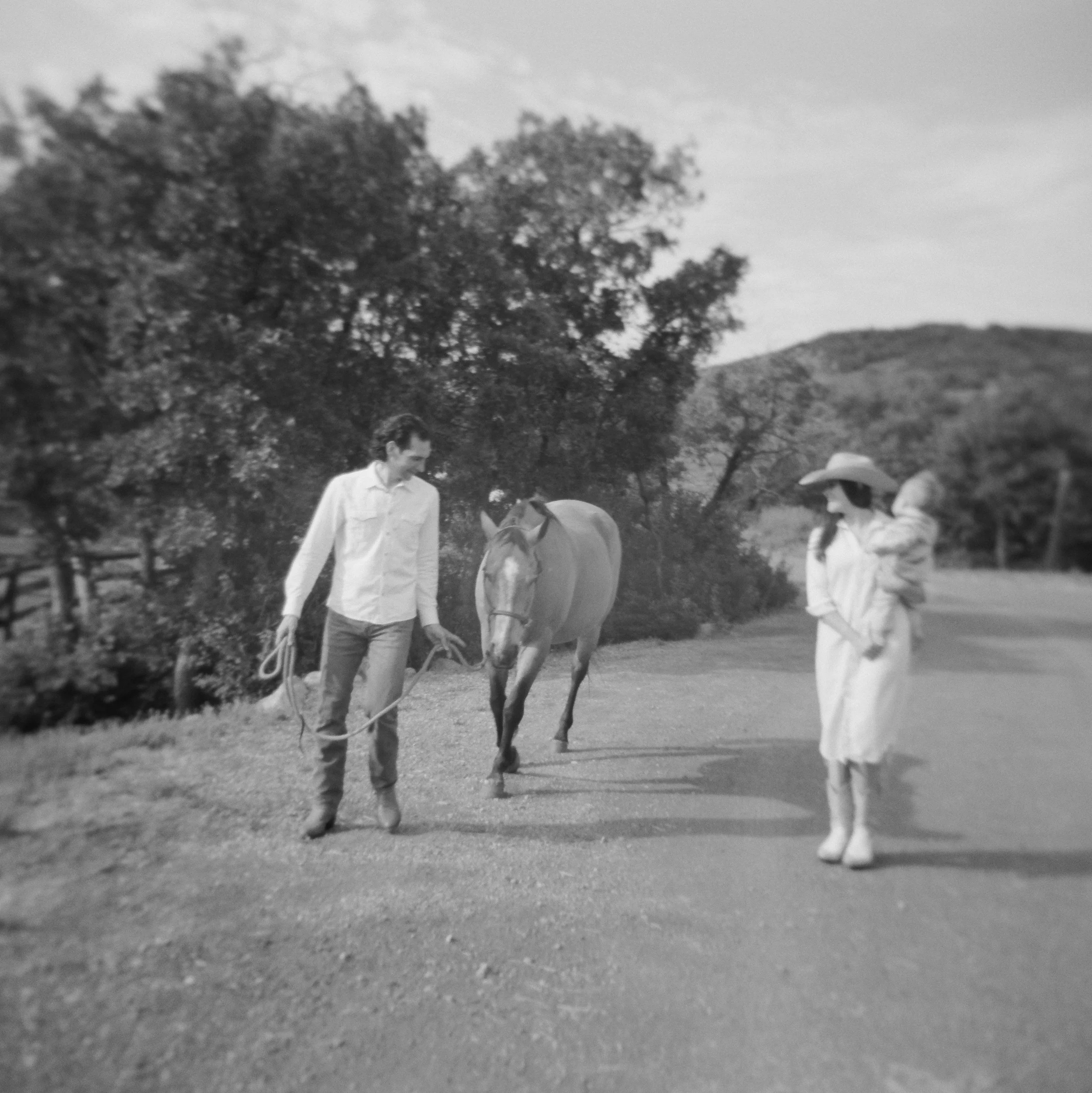 black and white family film photo at the lodge at blue sky park city utah walking on dirt road with horse