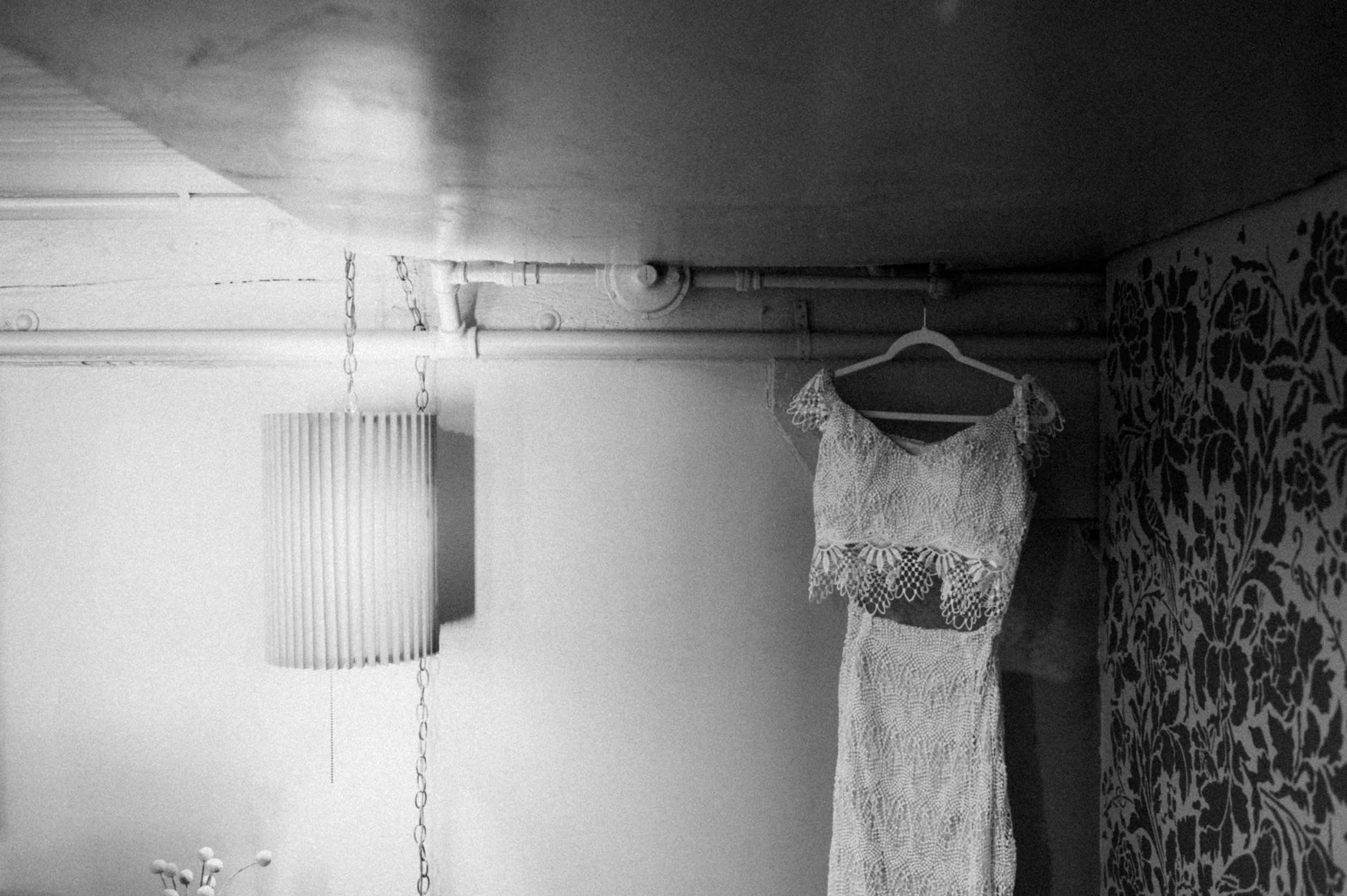artistic black and white image of two piece wedding dress next to moody lighting