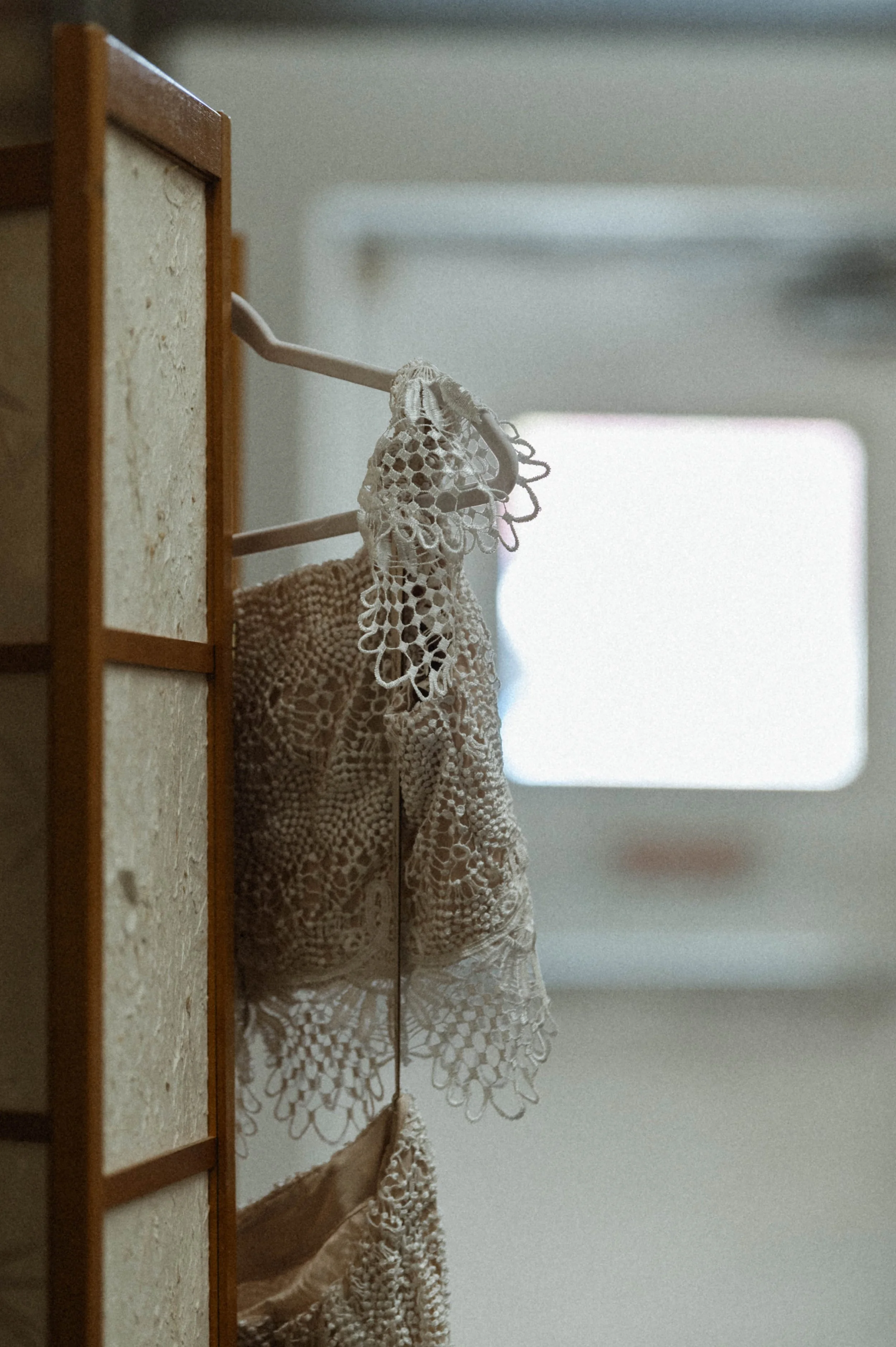 close up of beaded sheer lace wedding dress cap sleeve hanging up