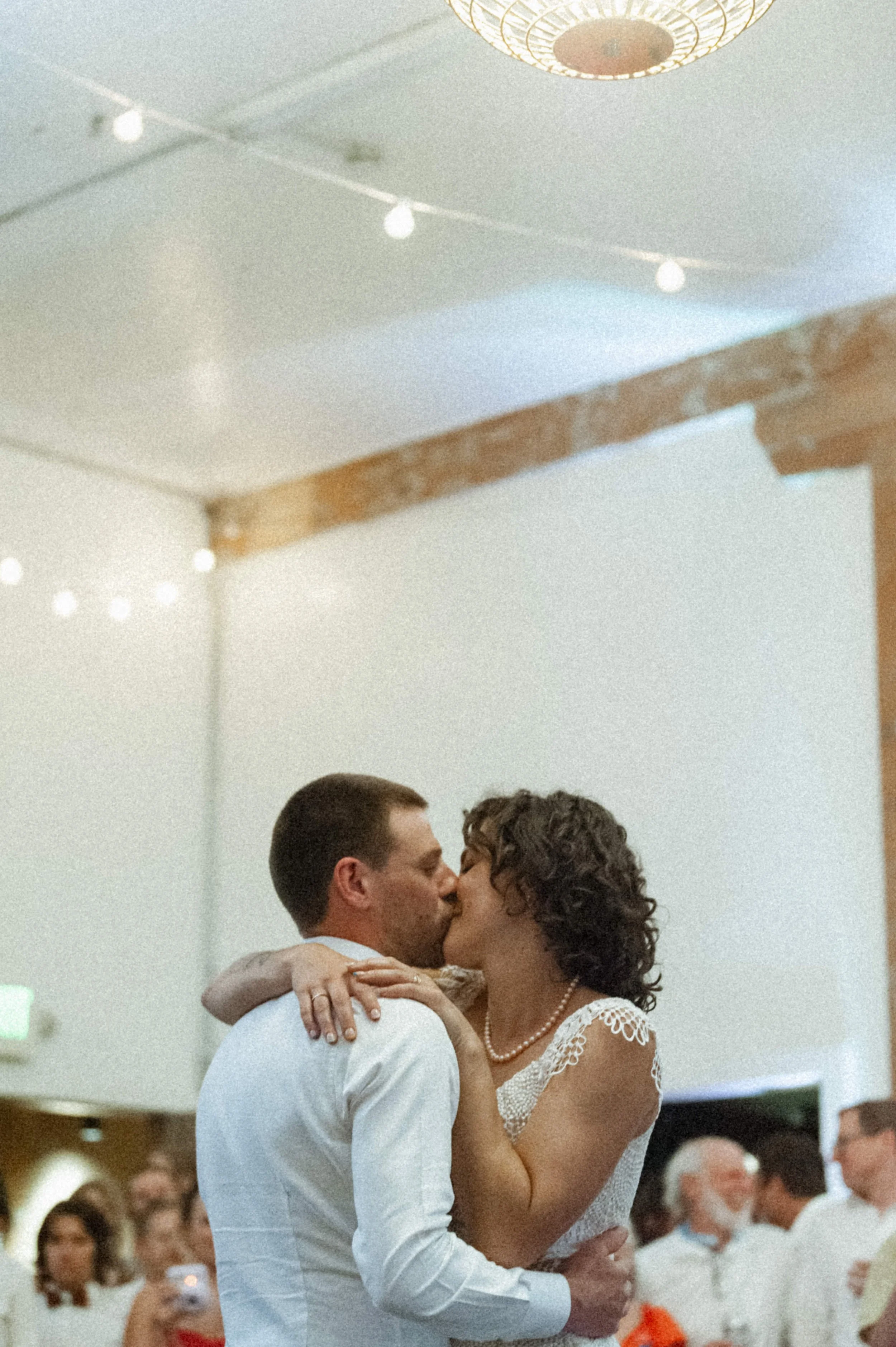 bride and groom kissing during first dance industrial style wedding white walls wooden beams