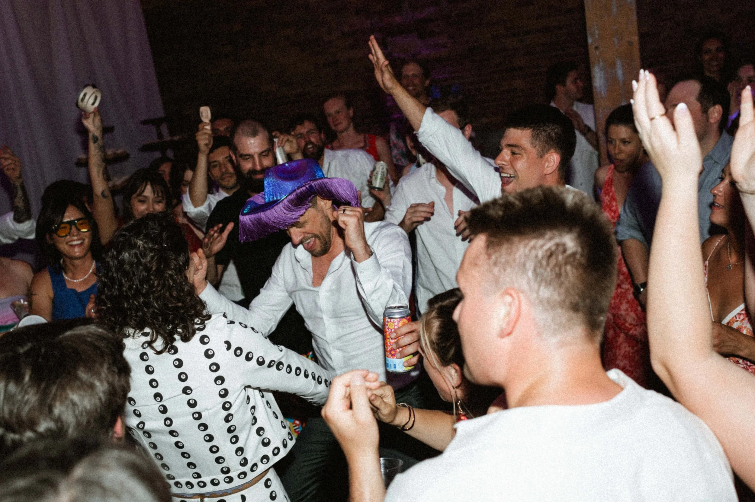Guests dancing under string lights in Ember's eclectic industrial reception space