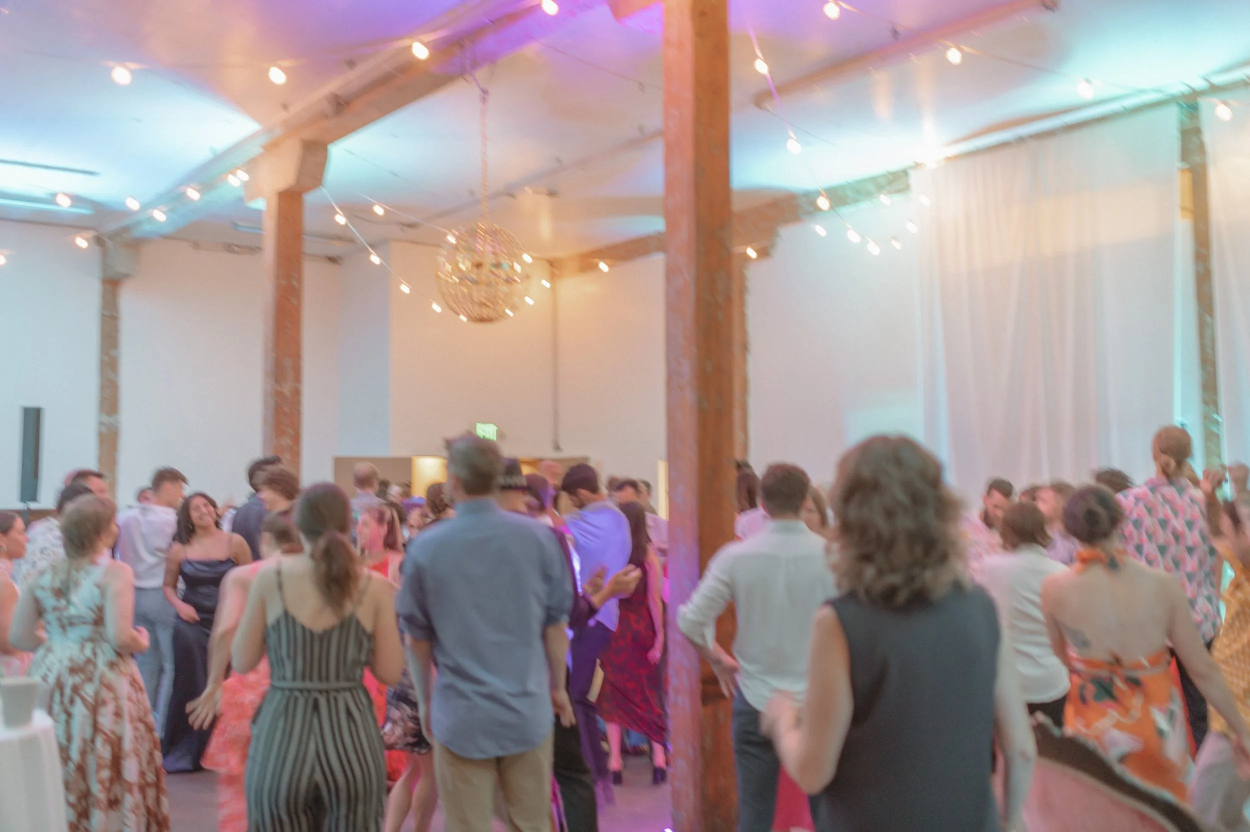 Guests dancing under string lights in Ember's eclectic industrial reception space