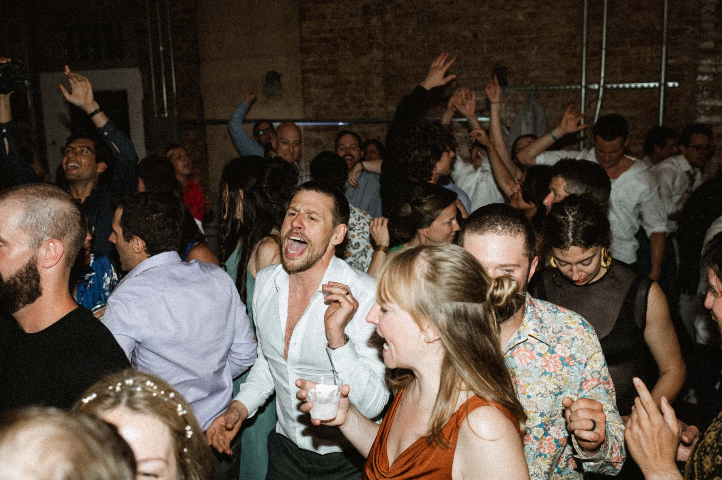 Guests dancing under string lights in Ember's eclectic industrial reception space