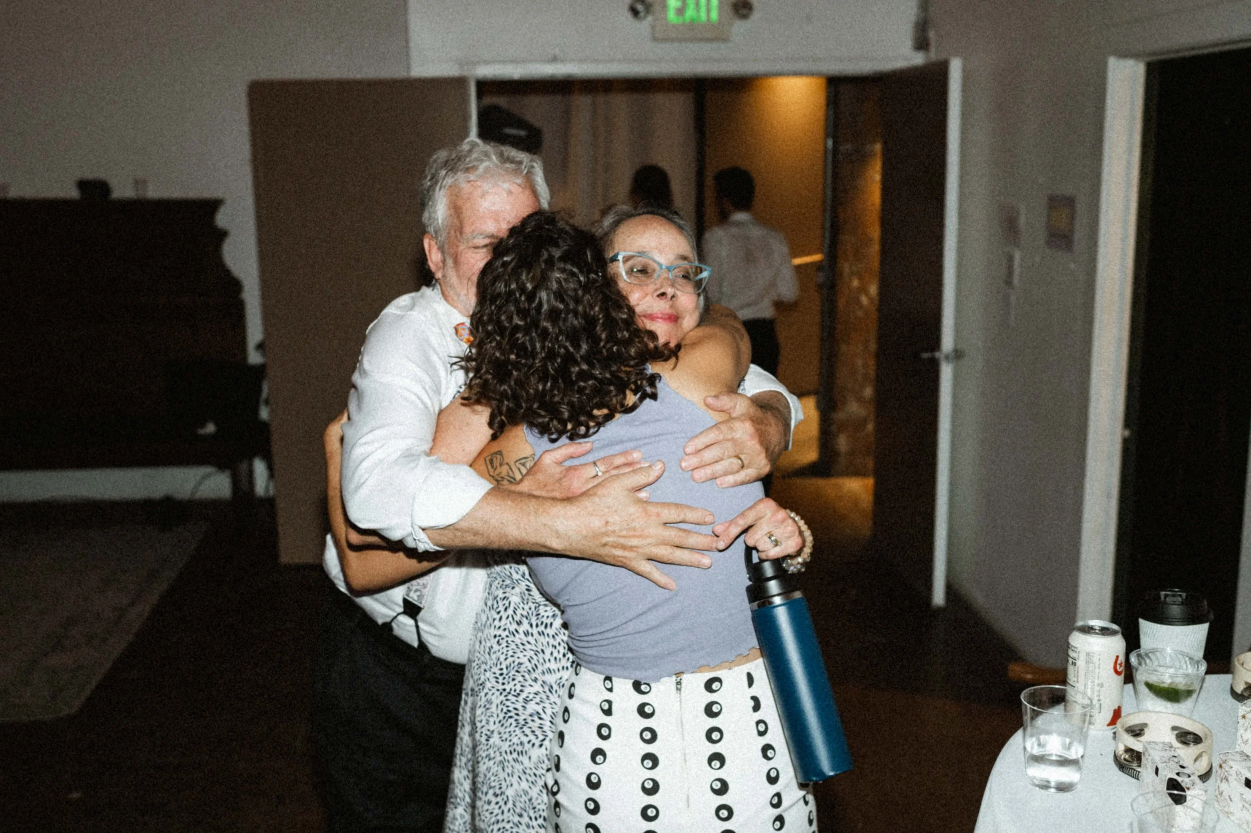 group hug with bride and parents industrial white wall wooden beams venue