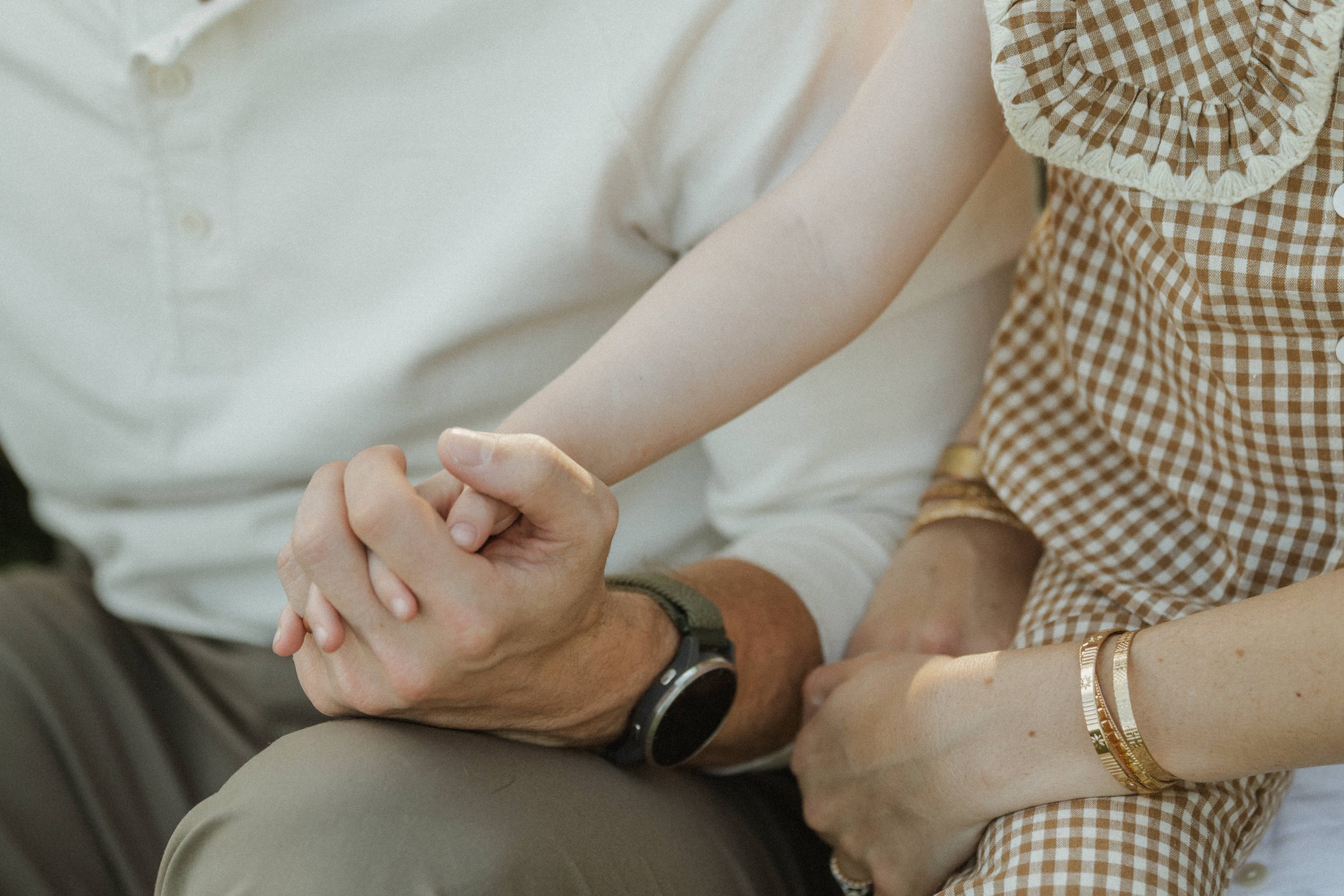 family of three holding hands with toddler