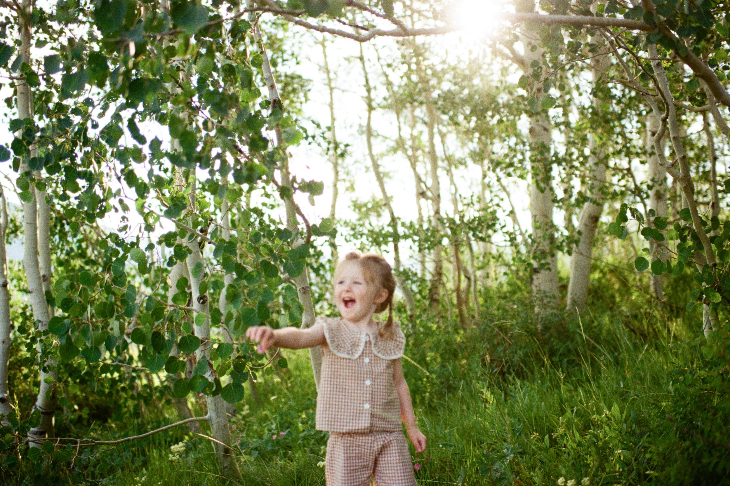 family film photo toddler laughing in mountains in golden light