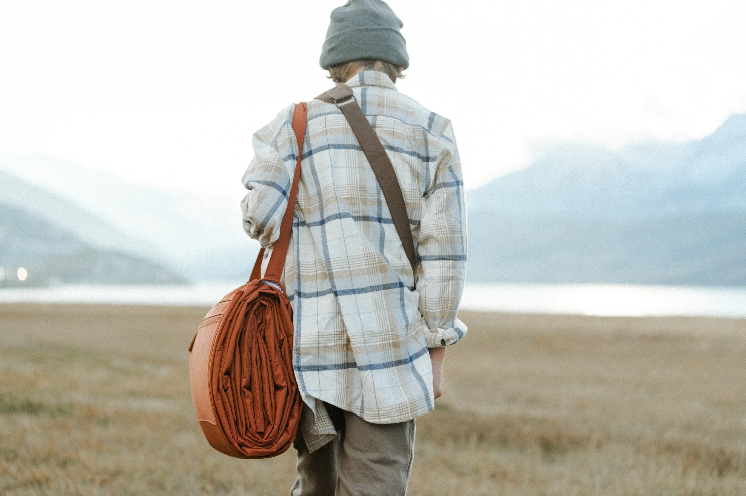 Small business product photographer capturing lifestyle shot of picnic blanket bag at golden hour by mountain lake
