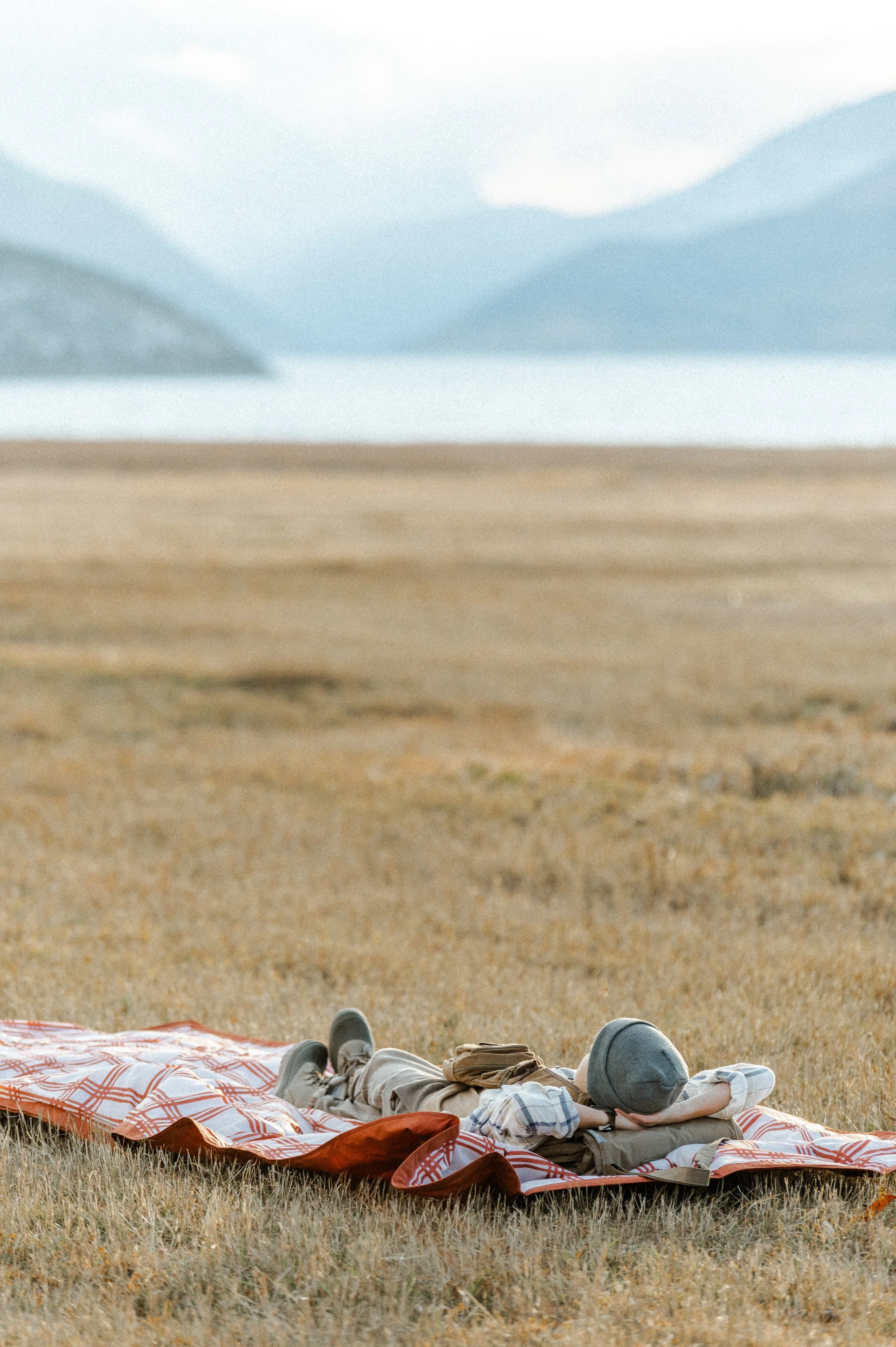 Small business product photographer capturing lifestyle shot of picnic blanket bag at golden hour by mountain lake