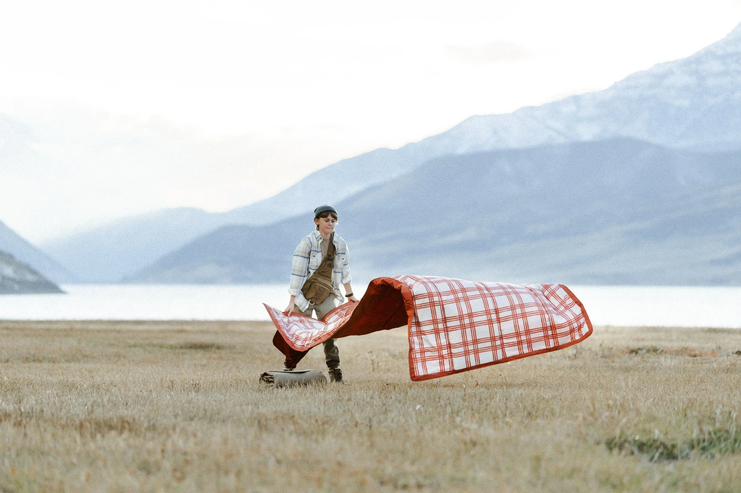 Picnic blanket flying in the wind during outdoor lifestyle product photography shoot near mountains