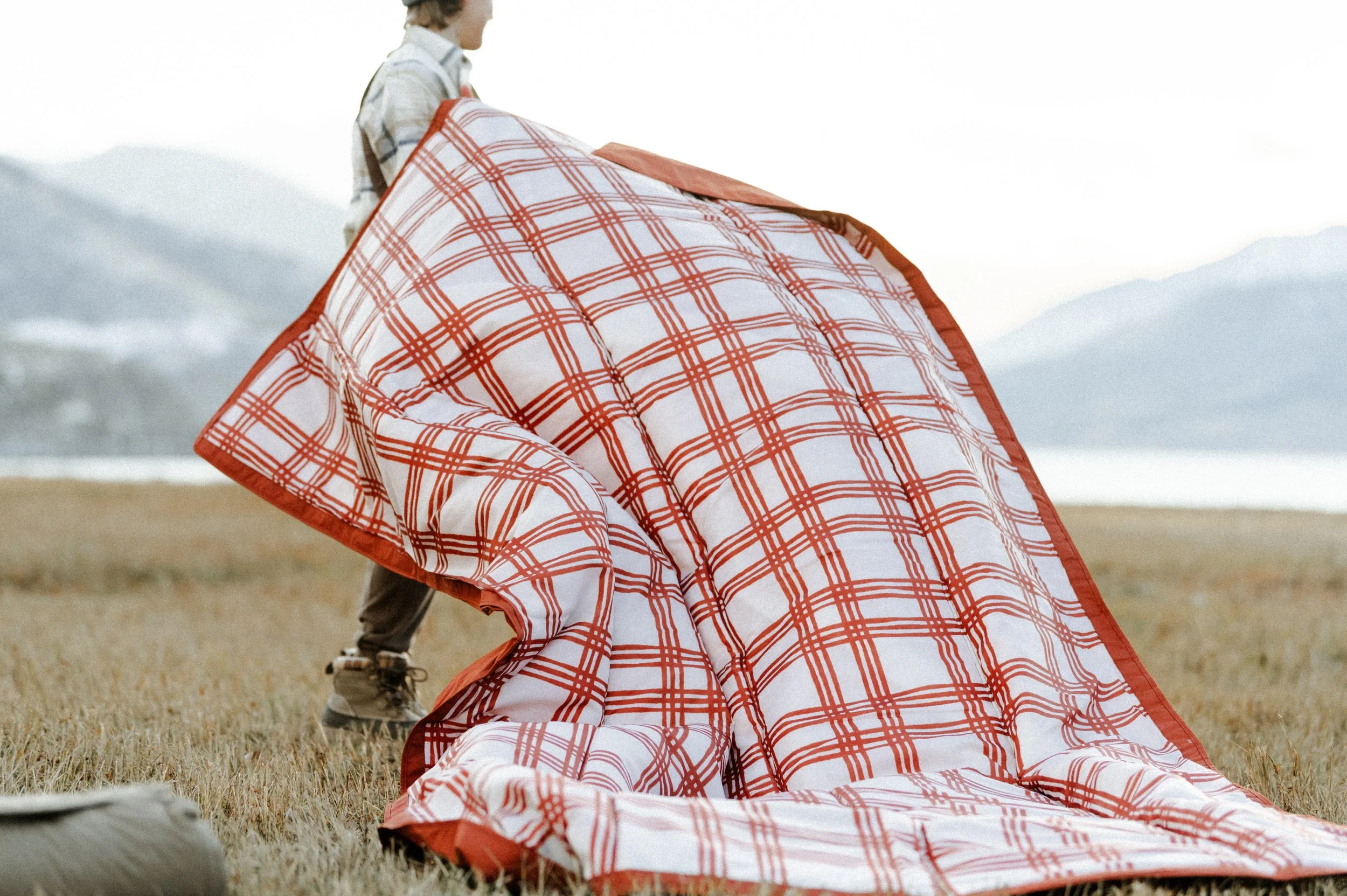 Picnic blanket flying in the wind during outdoor lifestyle product photography shoot near mountains
