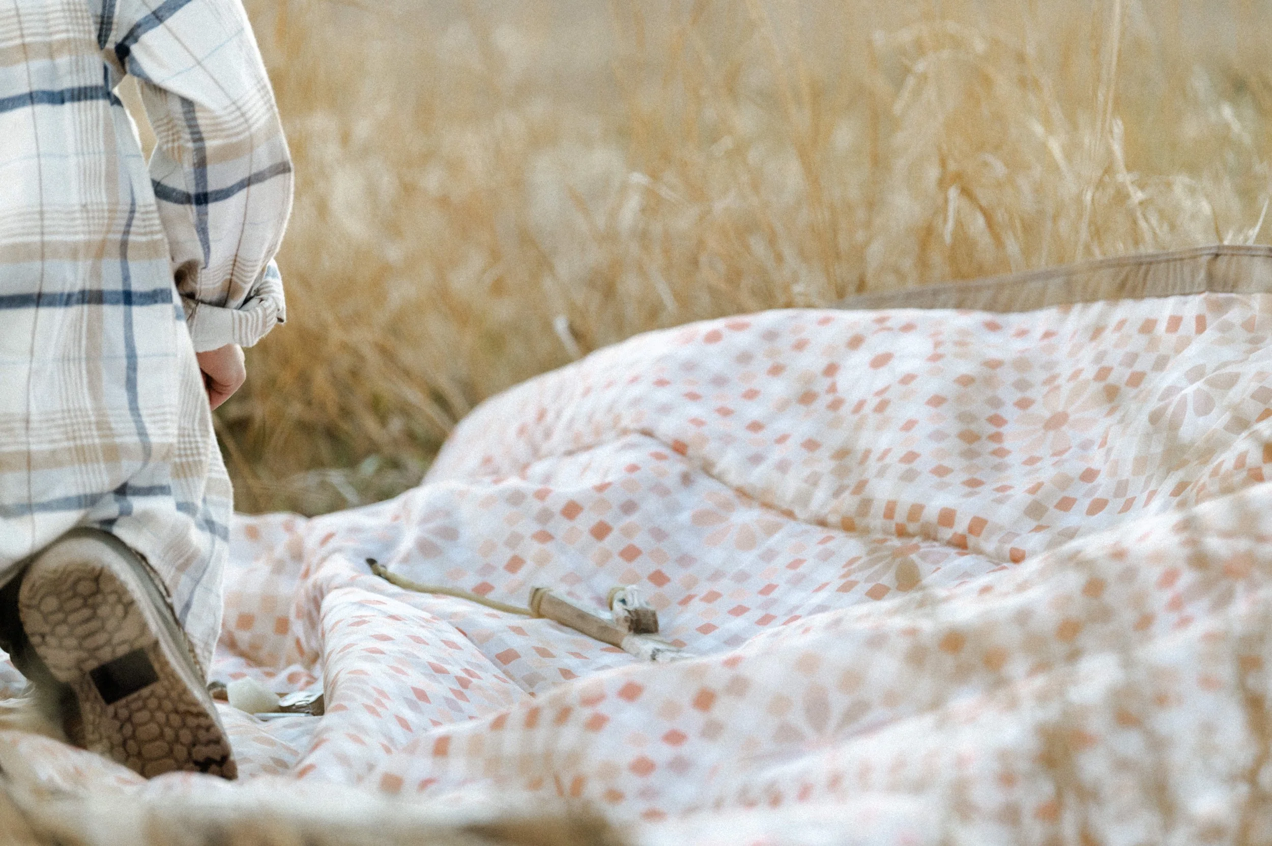 Kid stacking firewood next to camping picnic blanket, product photographer near me style shoot