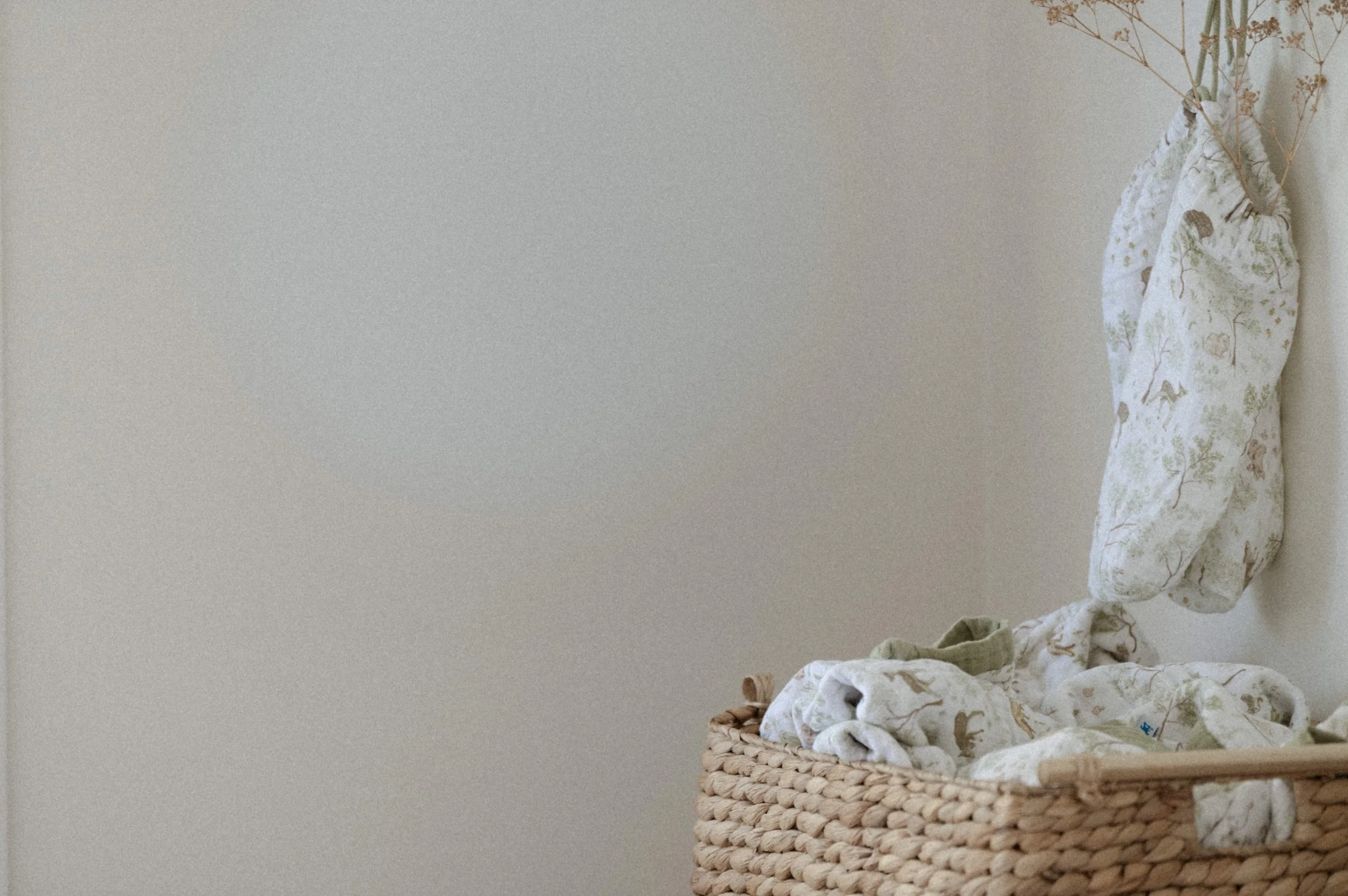 Lifestyle product photography of organic cotton quilt in woven basket, boho nursery styling