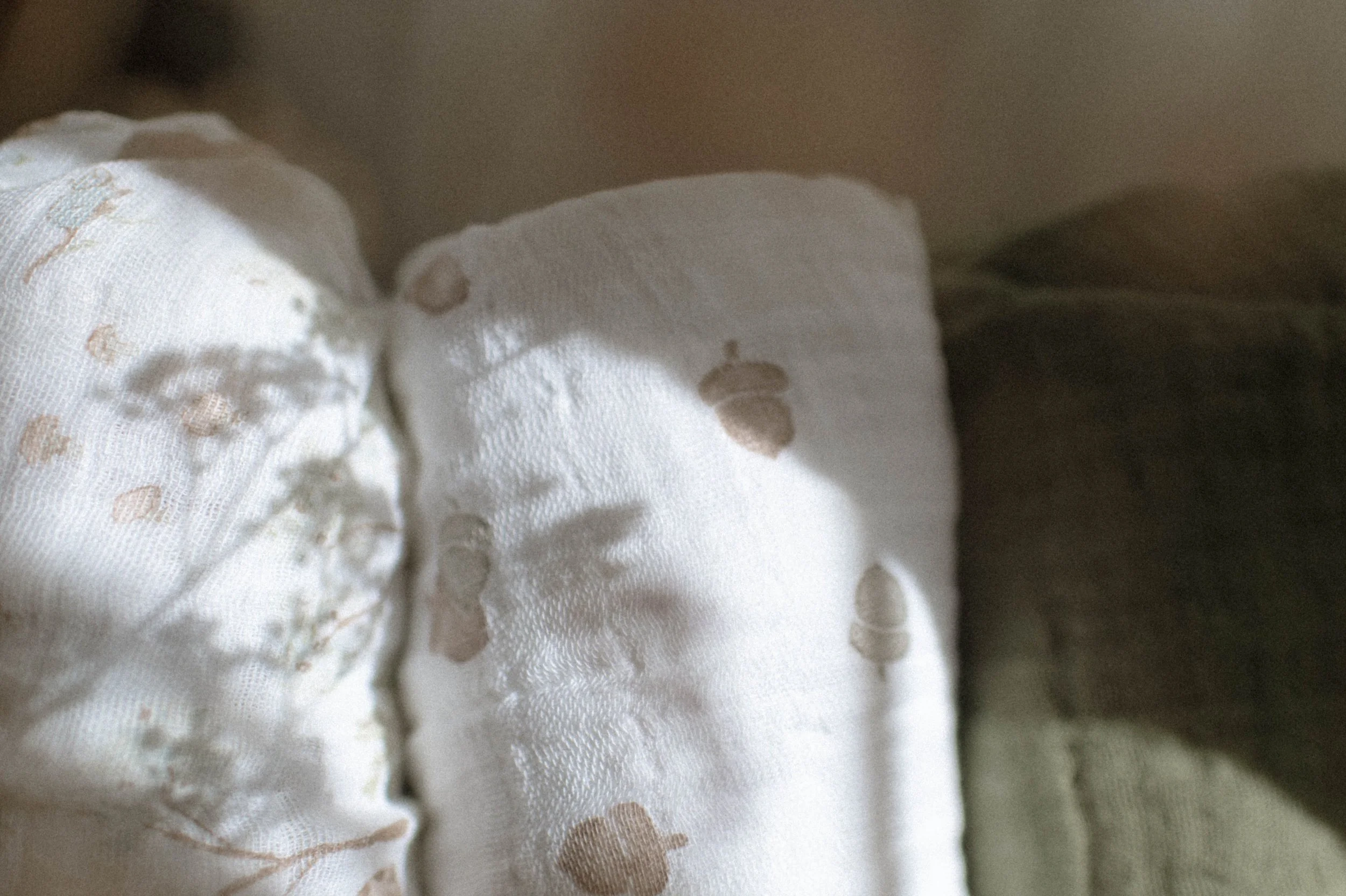 Lifestyle product photography of organic cotton quilt in woven basket, boho nursery styling