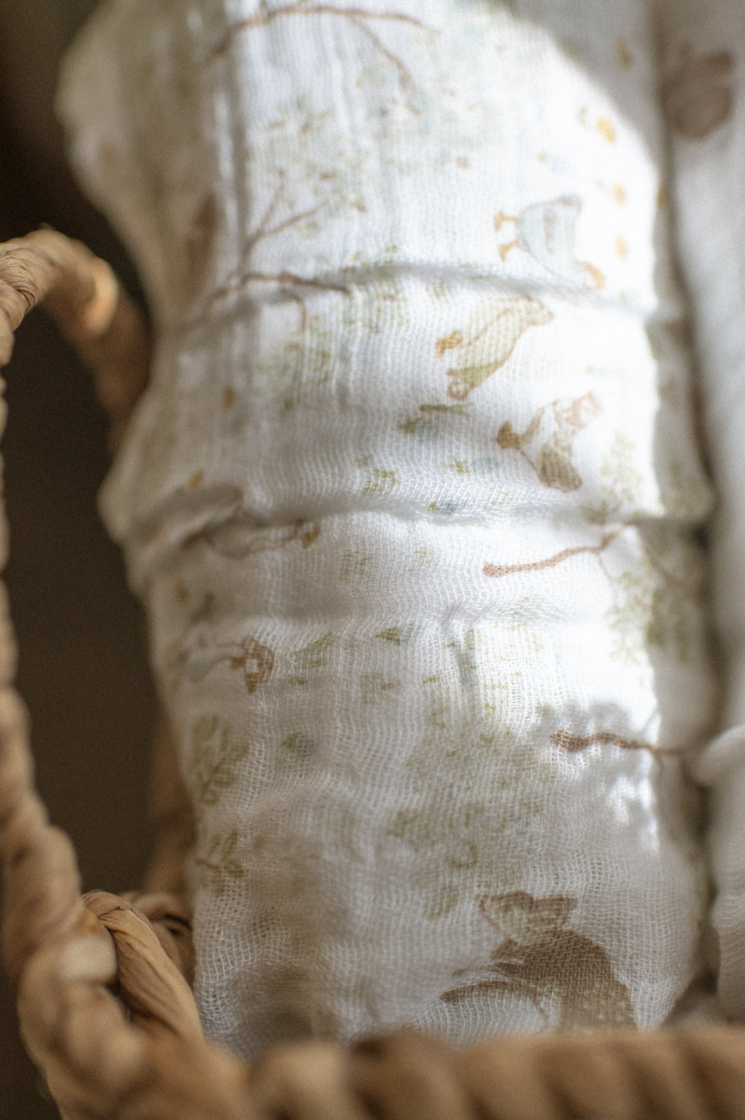 Lifestyle product photography of organic cotton quilt in woven basket, boho nursery styling