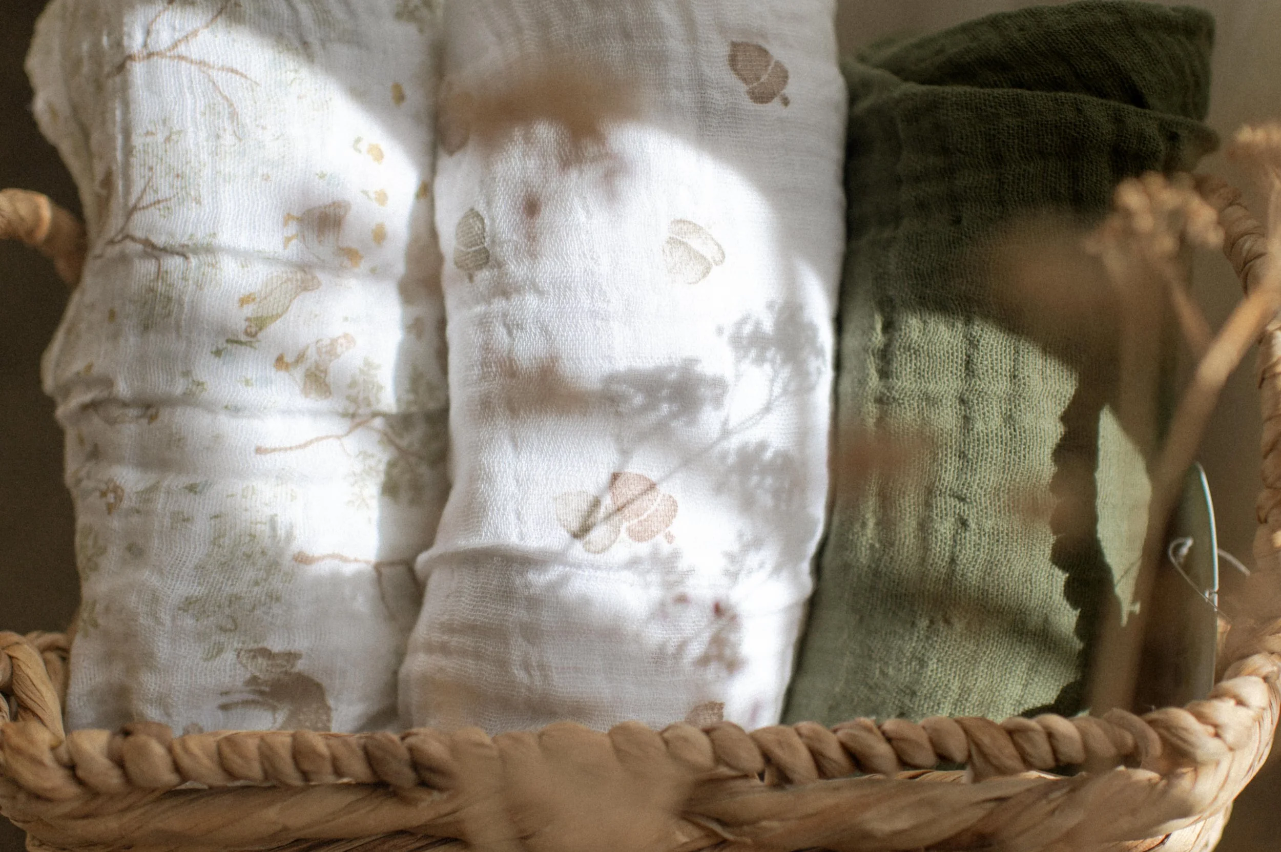 Lifestyle product photography of organic cotton quilt in woven basket, boho nursery styling