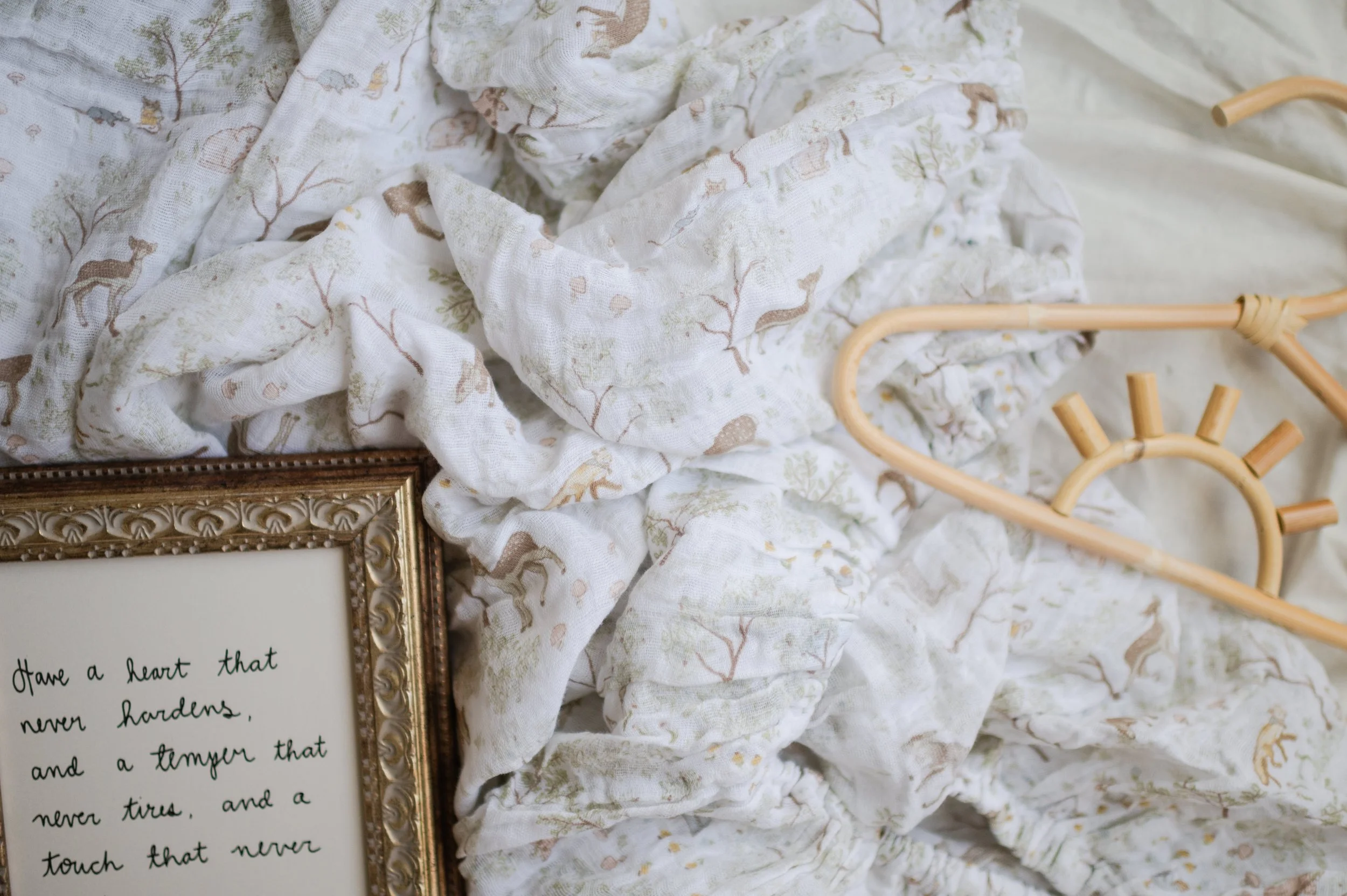 Styled flat lay of organic muslin crib sheet with rattan nursery decor and handwritten quote