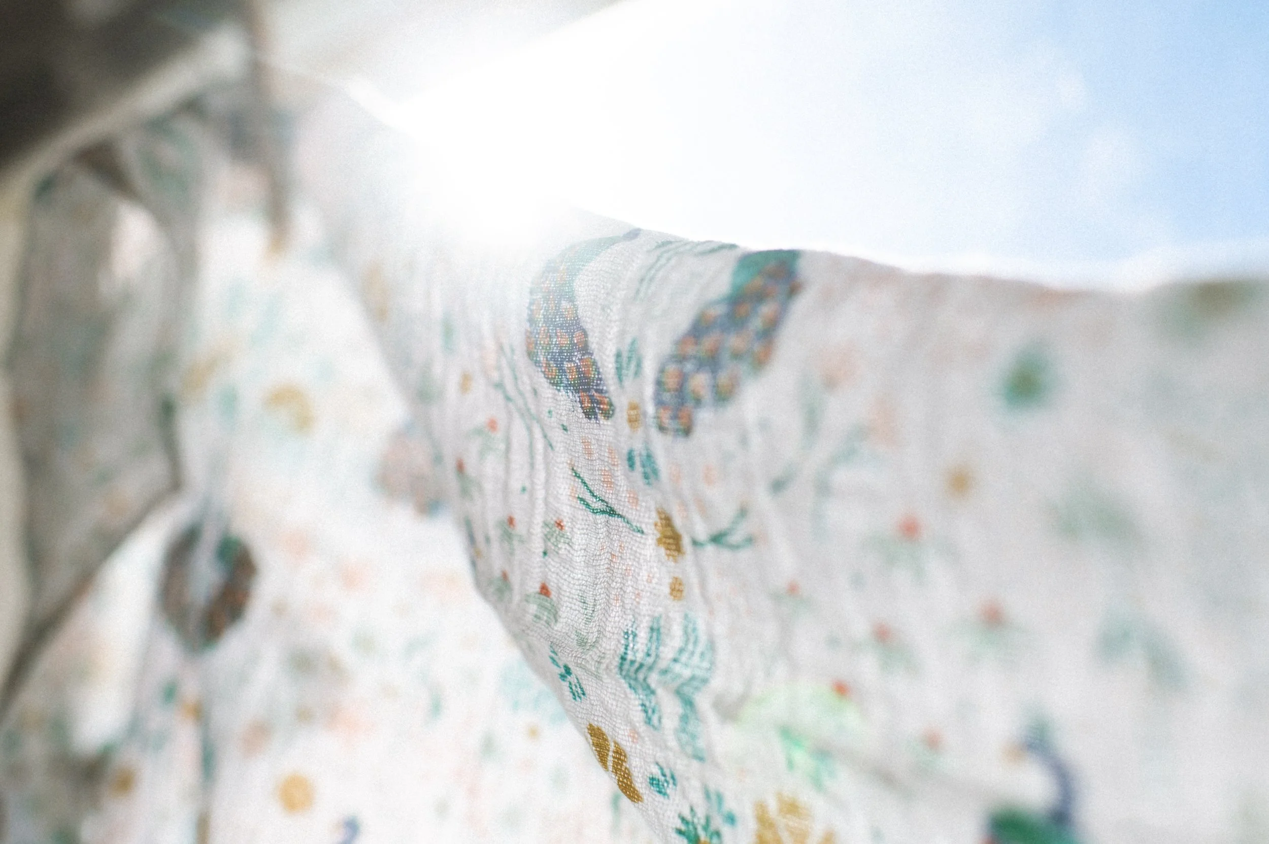 organic cotton peacock swaddle with sun backlighting