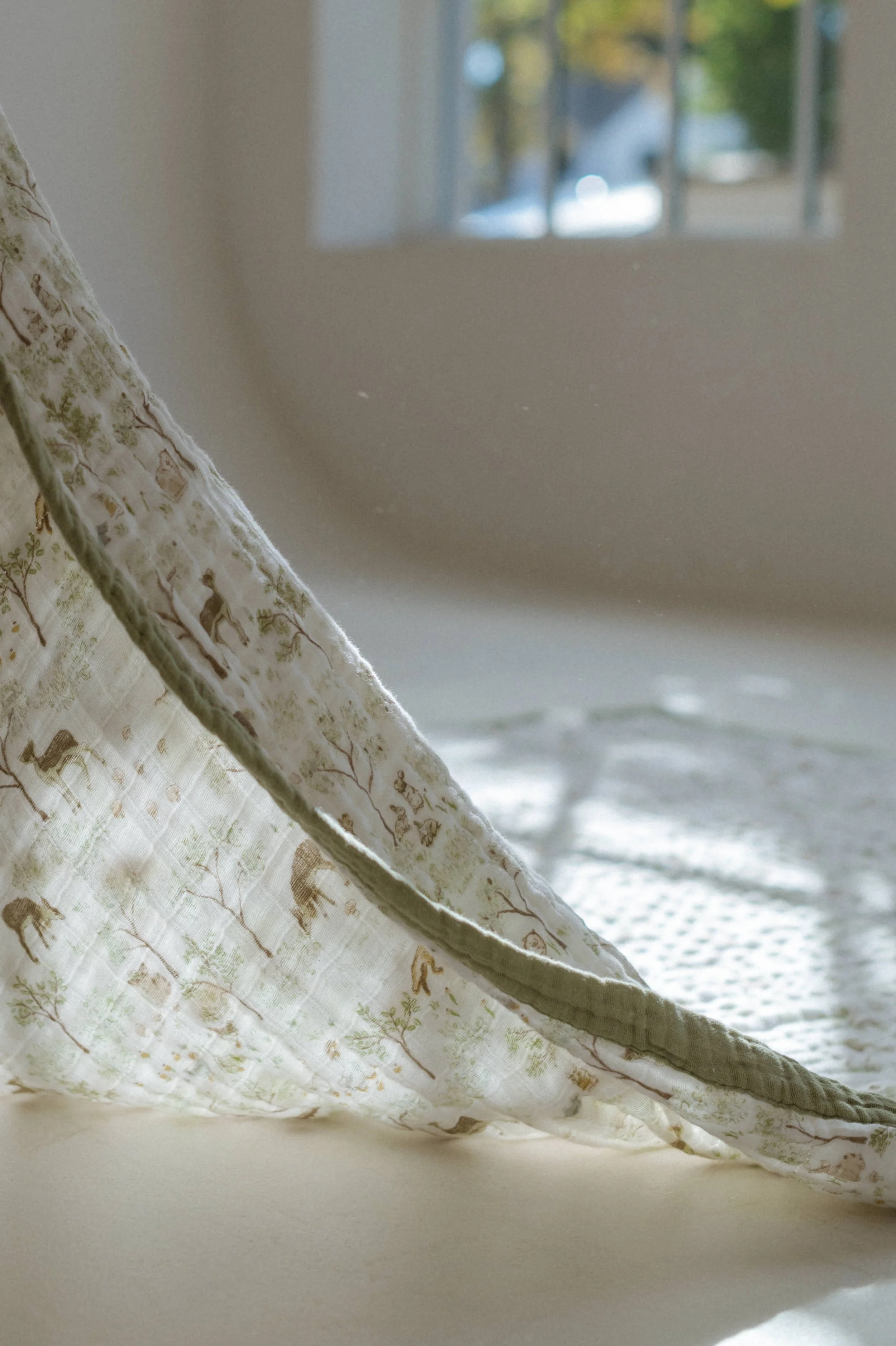 studio photo of organic cotton blanket with deer and trees backlit