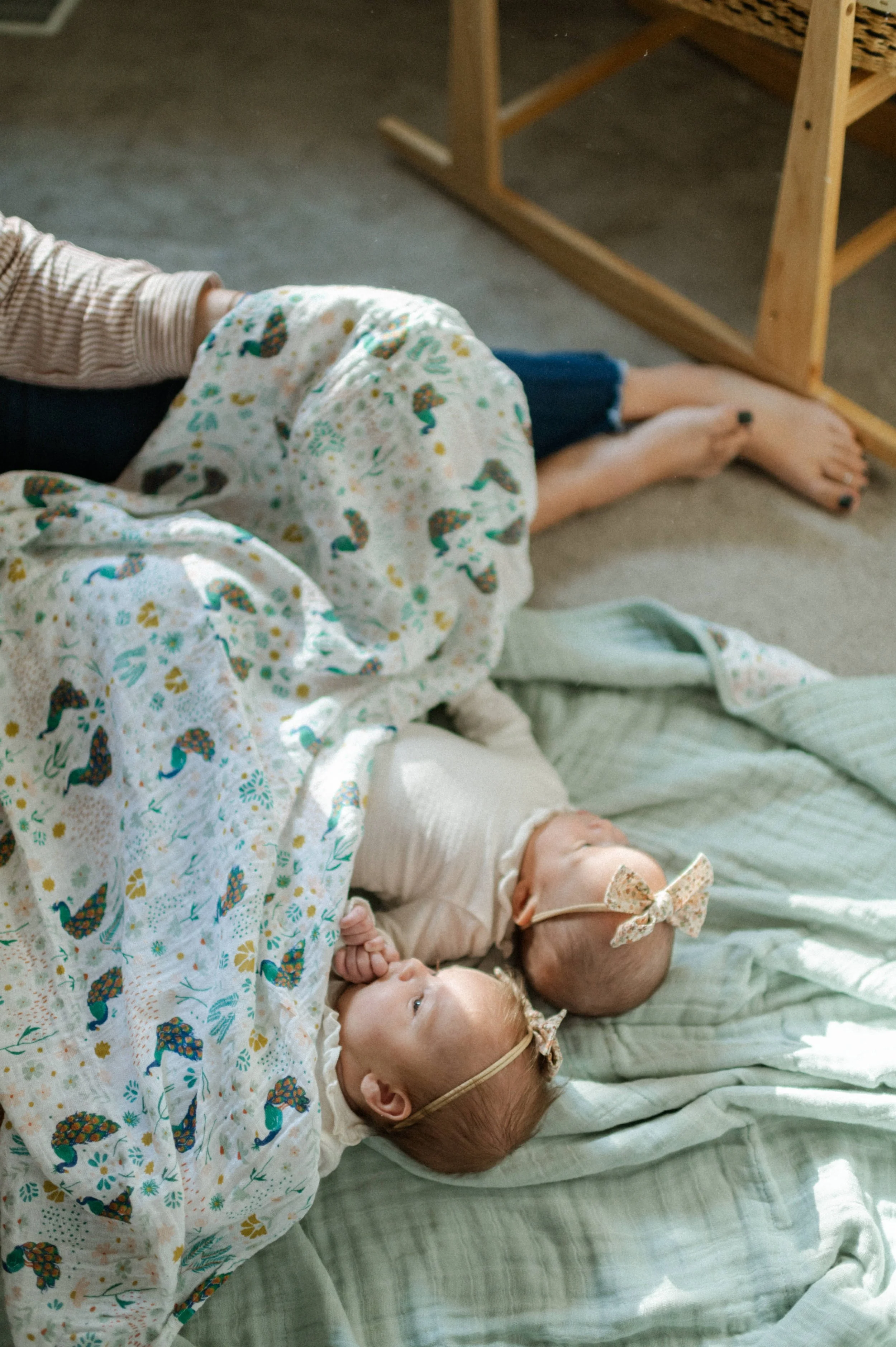twin baby girls with organic muslin cotton swaddle lying on top of blue organic cotton blanket