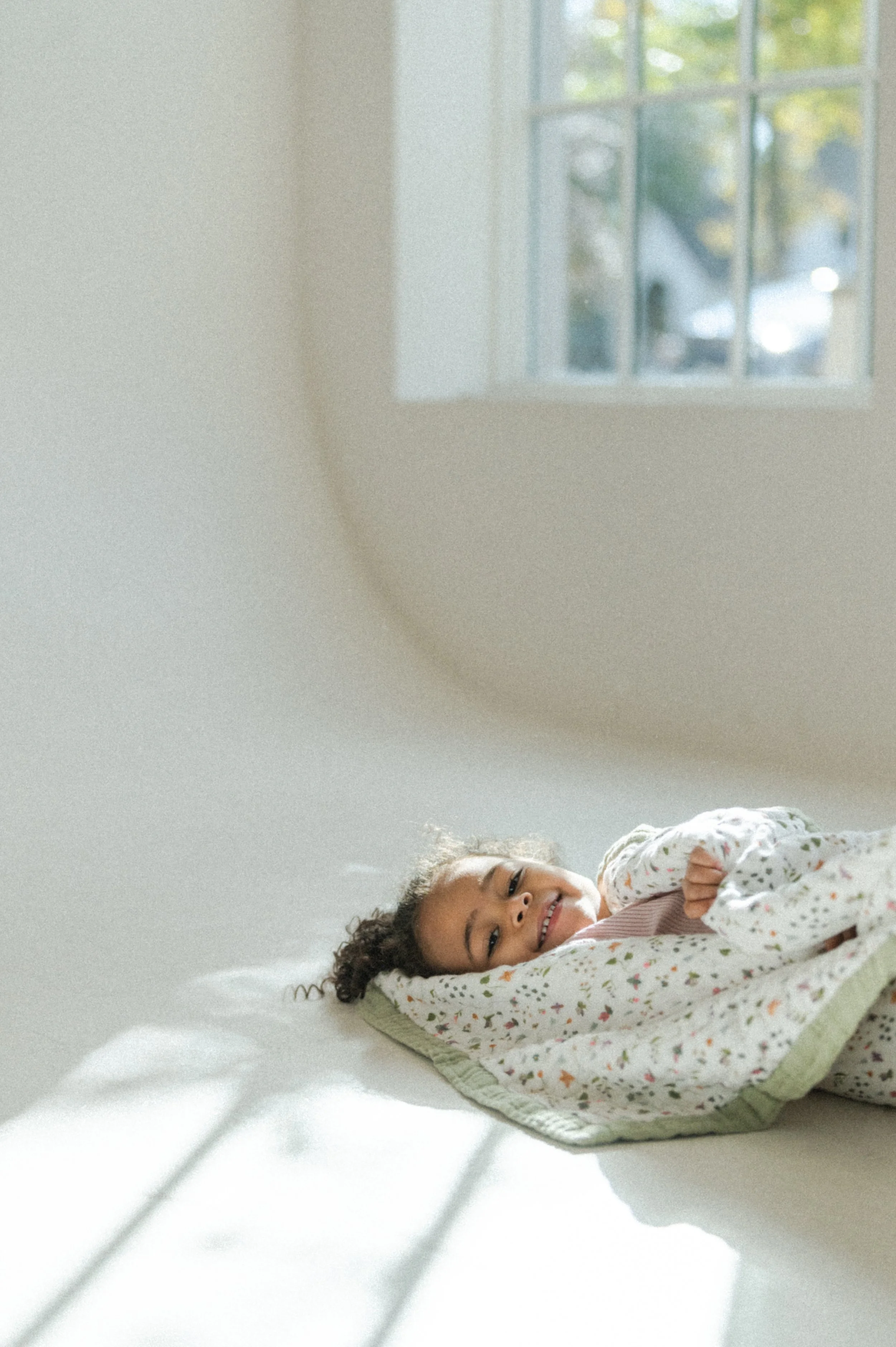 Lifestyle photo of toddler interacting with Garden Bees quilt in studio