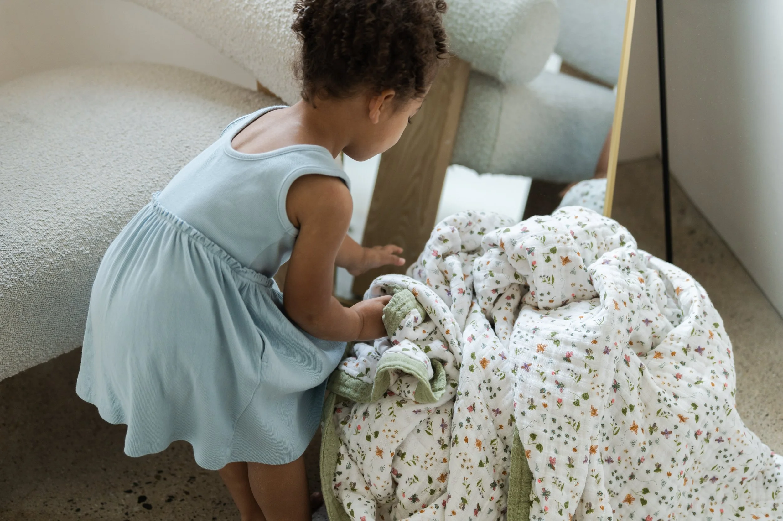 Lifestyle photo of toddler interacting with Garden Bees quilt in studio