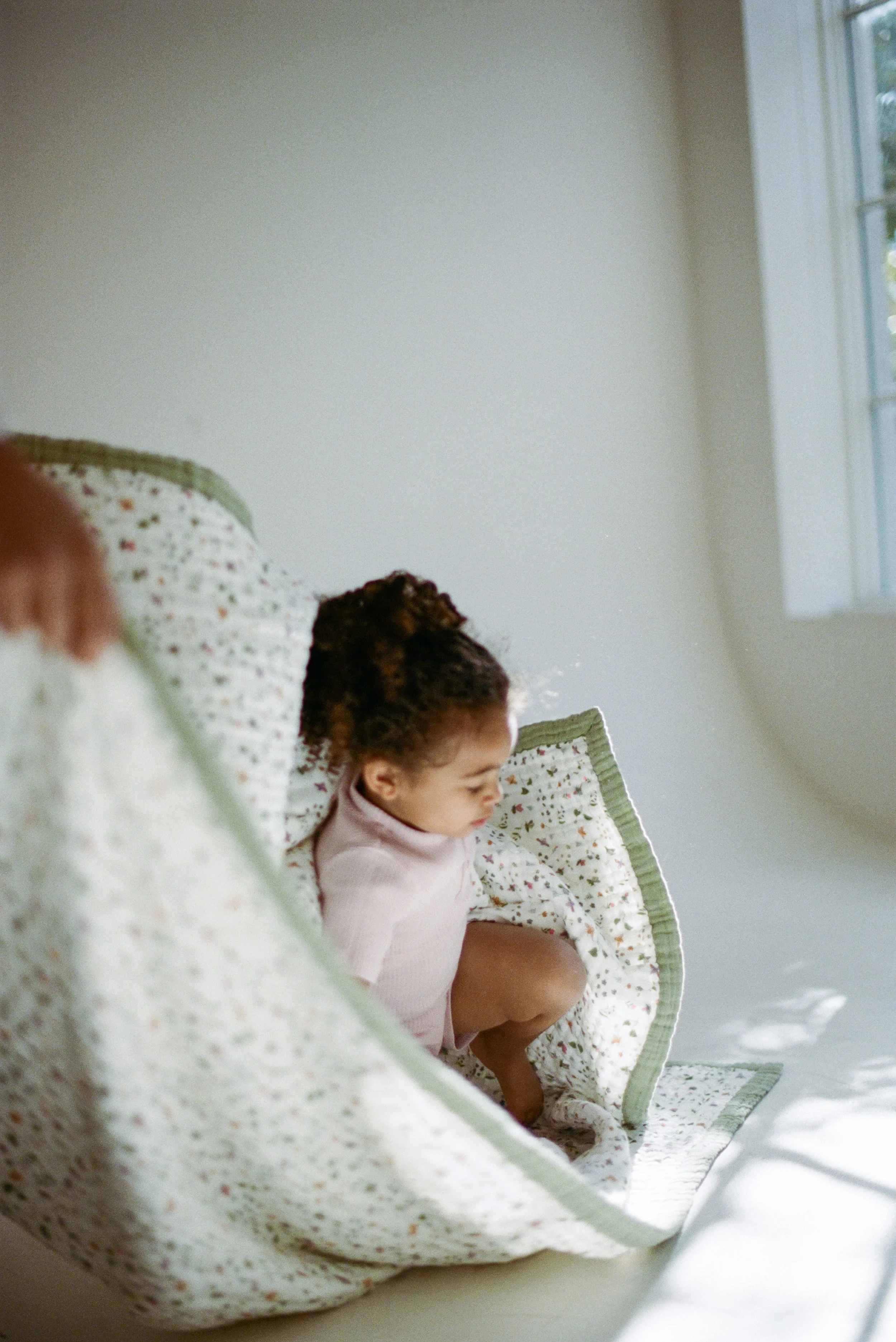 Lifestyle photo of toddler interacting with Garden Bees quilt in studio