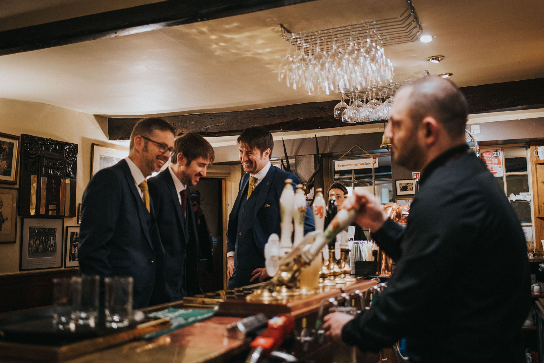 Candid unposed documentary wedding photography by Louise Jacob - Image of groom and groomsmen at the bar