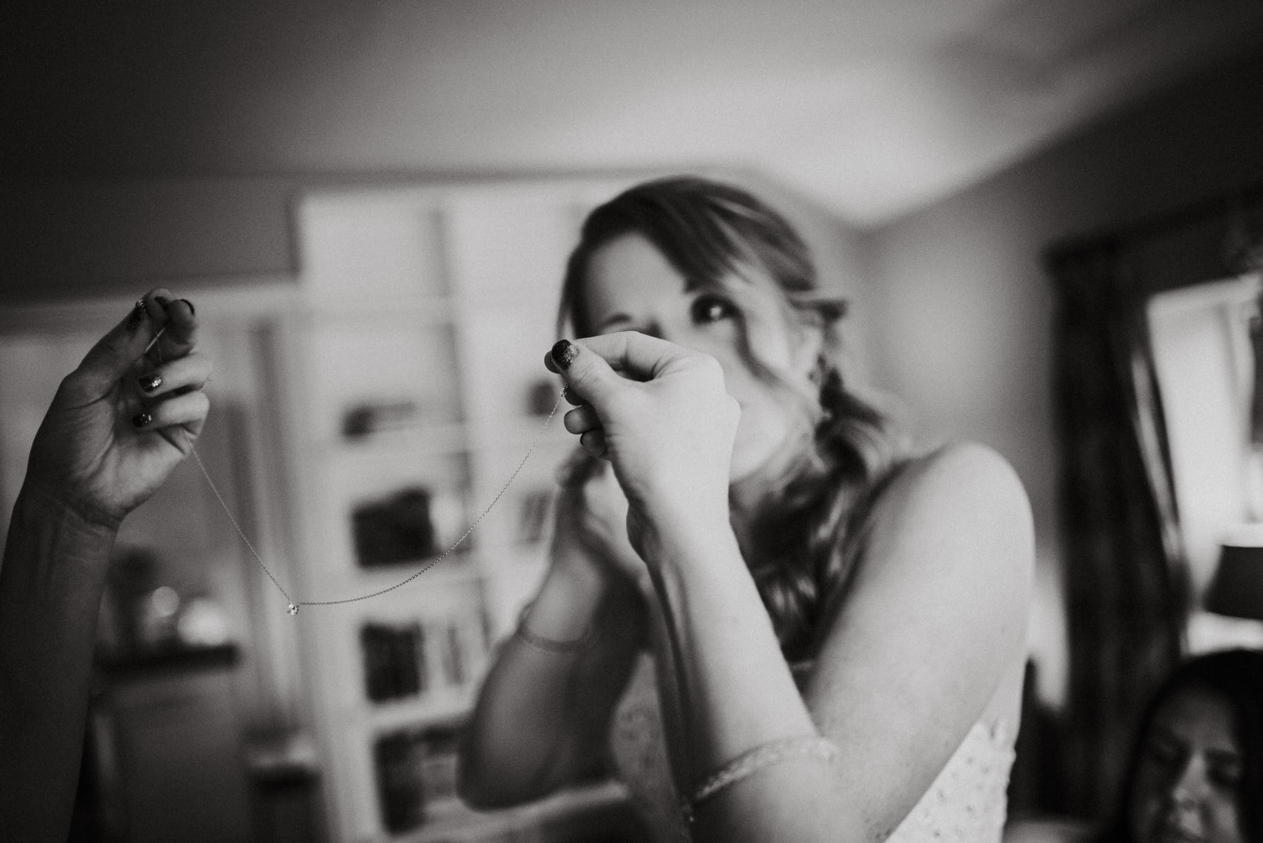 Cheshire documentary wedding photography by Louise Jacob - A bridesmaid putting on the brides necklace