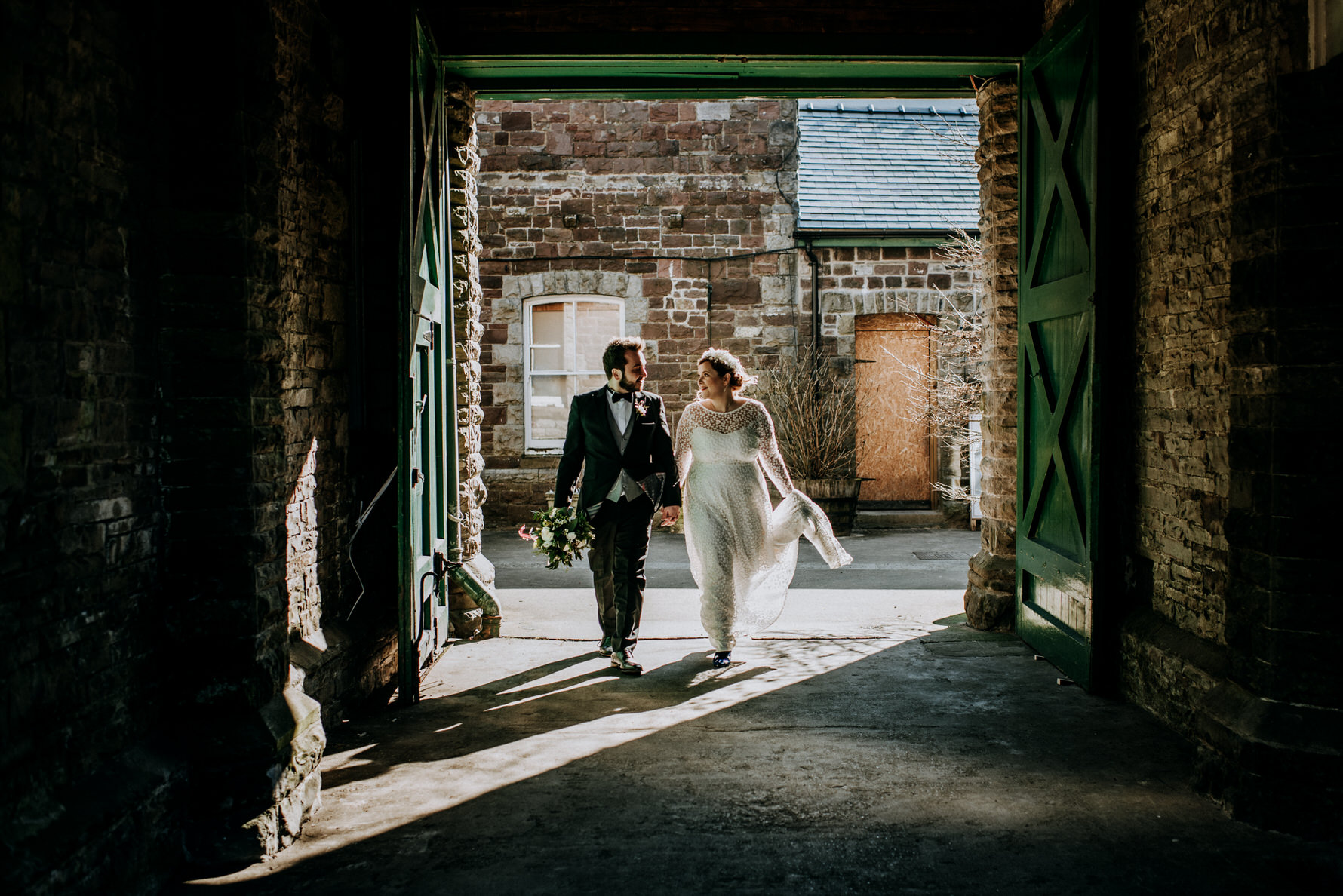 Wedding Photojournalism - A bride and groom walking through an archway