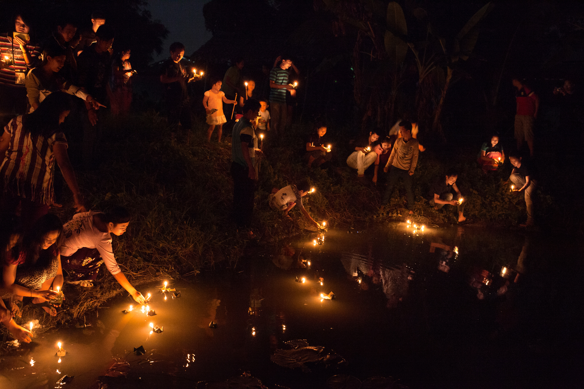  Des Birmans déposent des bougies sur l'eau d'une mare la nuit de Thadingyut. Cette date marque la fin du carême bouddhiste. Elle est l'occasion de festivités, de visites dans les temples et d'illuminations.

Province de Tak, Thaïlande, octobre 2014 