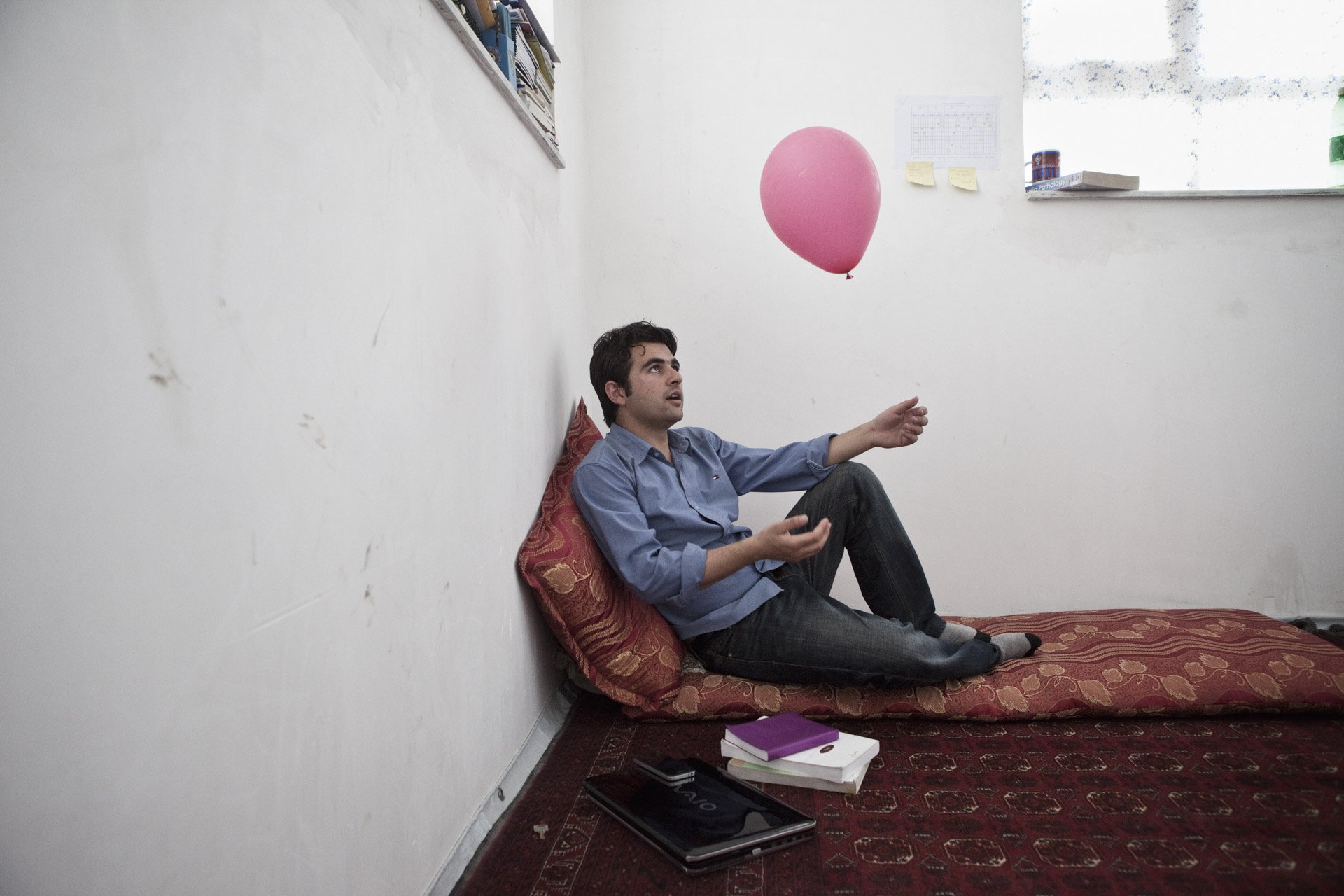  Dans sa chambre, Shamsul Aziz joue avec un des ballons du happening We Believe in Balloons organisé par un artiste américano-colombien : un lâcher de mille ballons roses dans la ville de Kaboul, en mai 2013, en symbole de paix. Sur son ballon, Sh