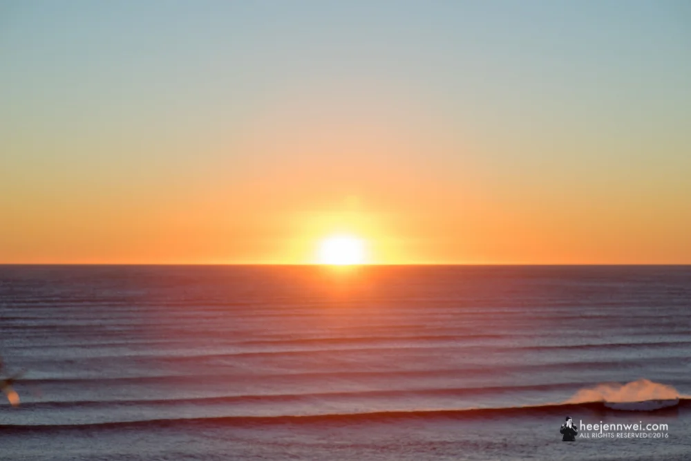 The sky lits up in orange palette as the sun sets into the sea. 