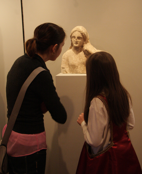 Visitors to the Exhibition Examine a Sculpture from Ancient Greece