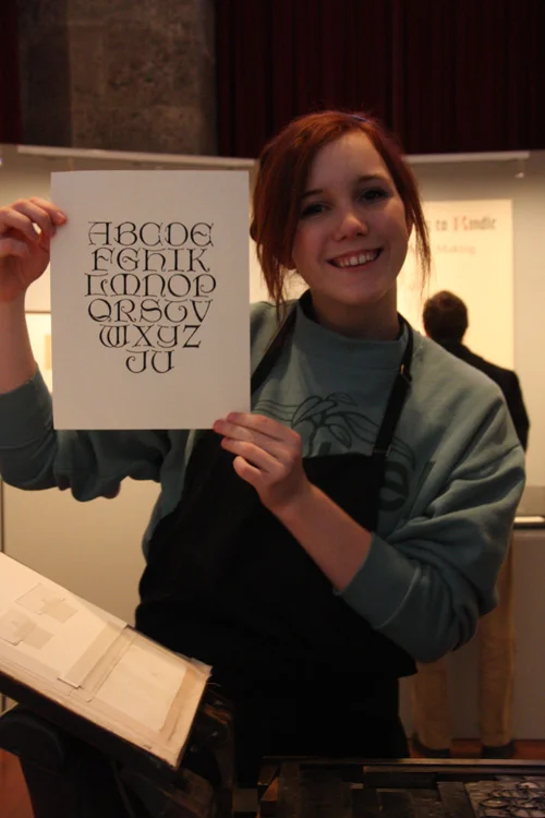 An Academy of the New Church Girls School student displays her printed page after taking a turn using the press.