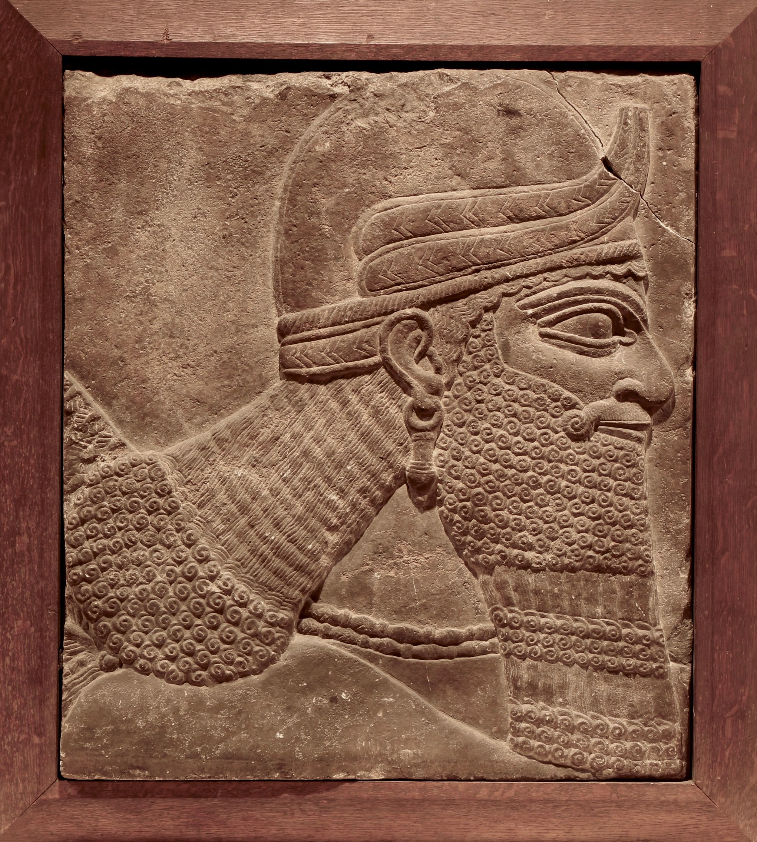 Figure 1: Head and shoulders of a genie, Northwest Palace of Ashurnasirpal II at Nimrud, Iraq. In the 19th and early 20th centuries Assyrian reliefs were often cut down and fitted into a wooden frame to signal their worthiness for purchase or display. (09.SP.1550; 61 x 54 cm)