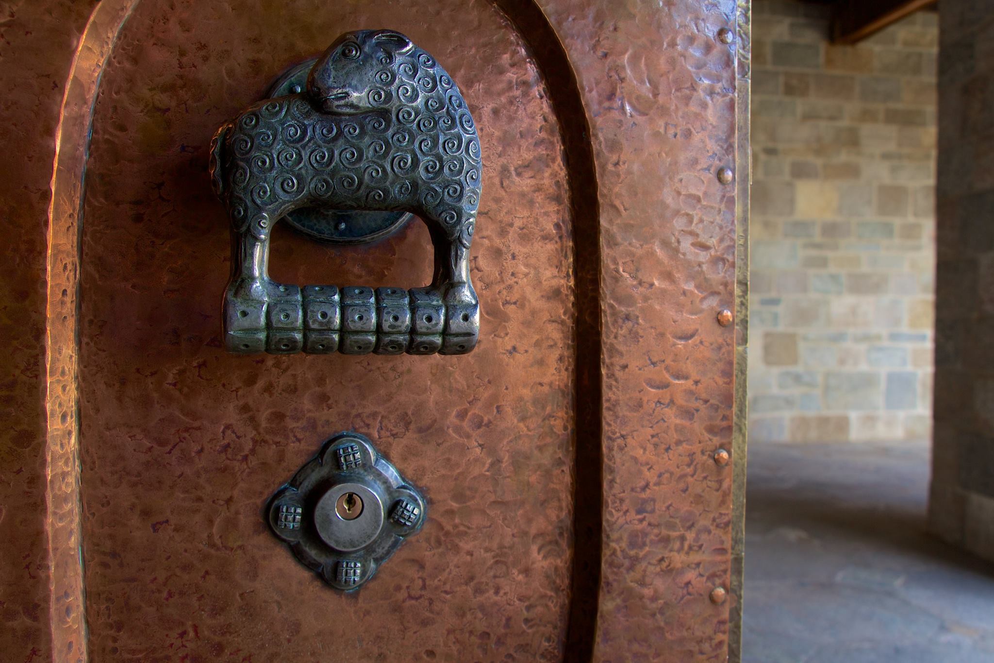 Figure 12: This massive bronze double door leading from the Great Hall to the Cloister features a hand-wrought Monel metal handle on each side. The left handle is a ewe, and the right is a ram.