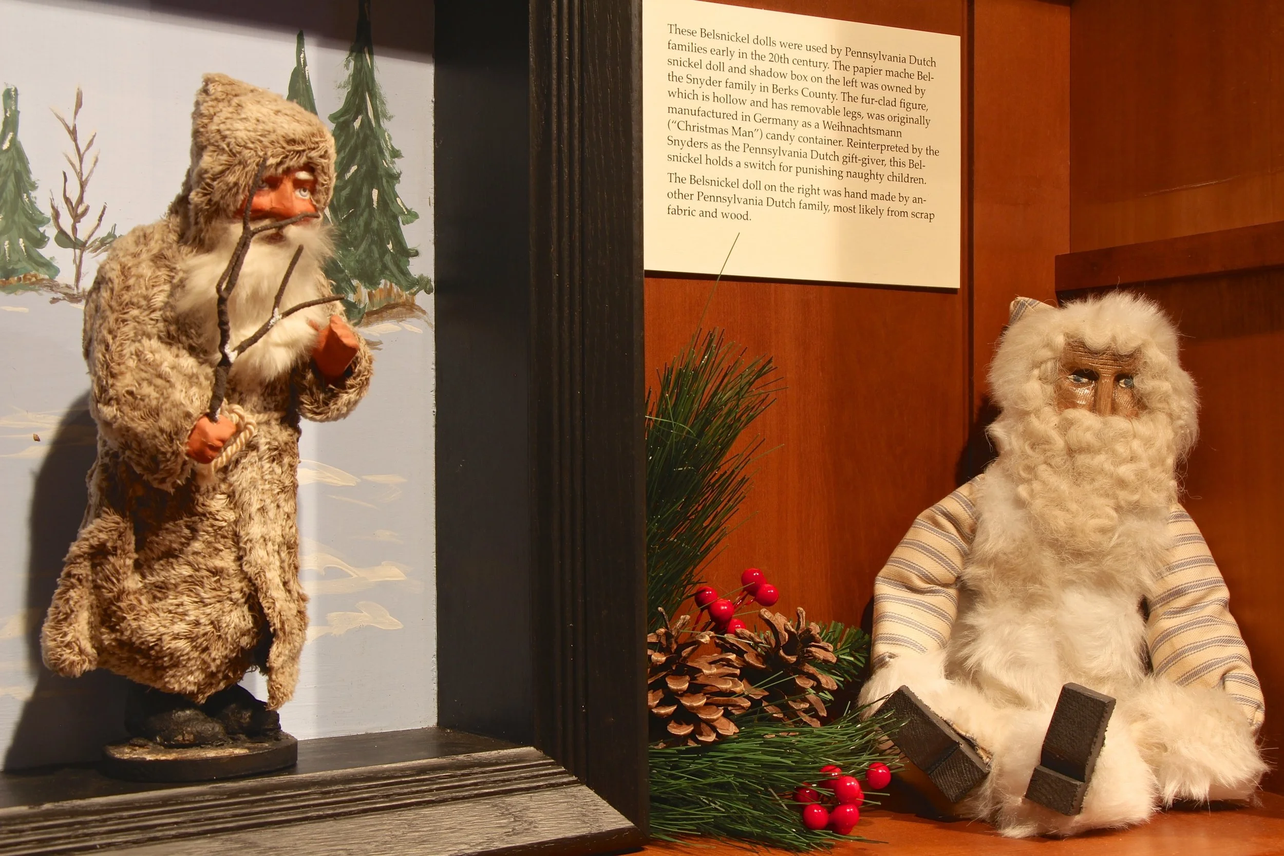 Figure 3: In Pennsylvania Dutch communities a Christmas gift giver known as Belsnickel made the rounds from farmhouse to farmhouse on Christmas Eve. The name Belsnickel is derived from German and means “St. Nicholas dressed in fur.” This Pennsylvania Dutch “Nicholas” came carrying treats or presents to reward obedient children who could recite a Bible verse or say a prayer. However, Belsnickel was also ready with a rod, switch, or buggy whip to punish any badly behaved children. The Belsnickel dolls pictured here were used by Pennsylvania Dutch families early in the 20th century. On loan from the Pennsylvania German Cultural Heritage Center at Kutztown University.