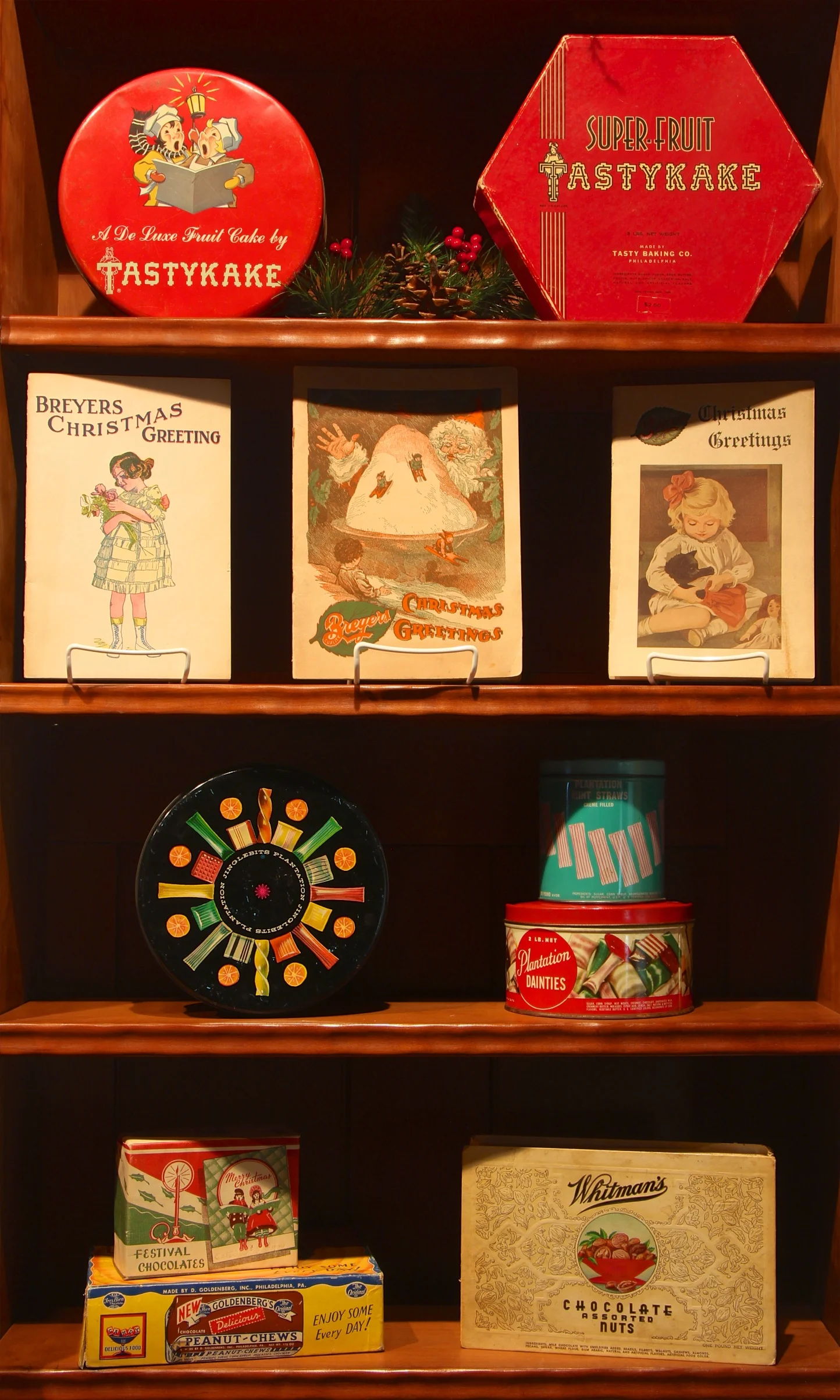 Figure 15: Candy, cake and ice cream have been a favorite part of Christmas celebrations in Philadelphia since early in the 19th century. Some of the largest sugar refineries in the world were located in the city, and a number of candy manufacturers made Philadelphia their home, such as Whitman’s, H.O. Wilbur & Sons (Wilbur Buds), and Goldenberg’s Peanut Chews. Special products, such as Tastykake’s De Luxe Fruit Cake, were made especially for the Christmas season. Objects on loan from the National Christmas Center and Museum, Lancaster, PA.