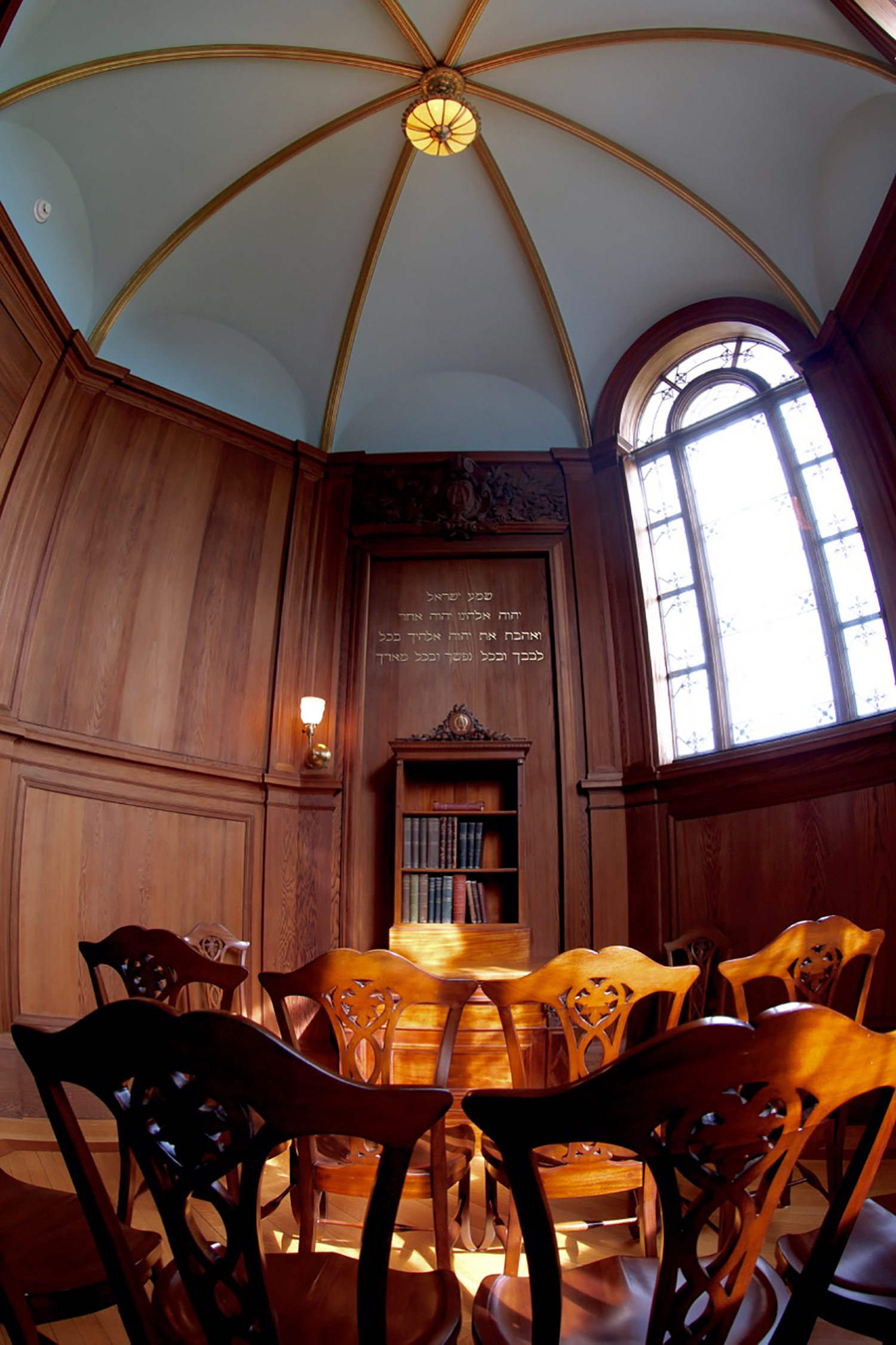 Figure 3: The walls of Cairnwood’s chapel are lined with California redwood, and the ceiling is finished in blue with ribs of gold. The home was dedicated on May 22, 1895. During the dedication service, the Bible and volumes of the theological works of Emanuel Swedenborg were placed in the chapel in a special mahogany cabinet. The Pitcairns had originally commissioned the cabinet for their home in Philadelphia, where it hung on the east wall of their parlor. (It was made in 1888 by G. Vollmer & Son, 1108 Chestnut Street, Philadelphia.) The wall is painted with an inscription in Hebrew in gilded letters: “Hear, O Israel: The Lord our God, the Lord is one! You shall love the Lord your God with all your heart, with all your soul, and with all your might” (Deuteronomy 6:4–5).