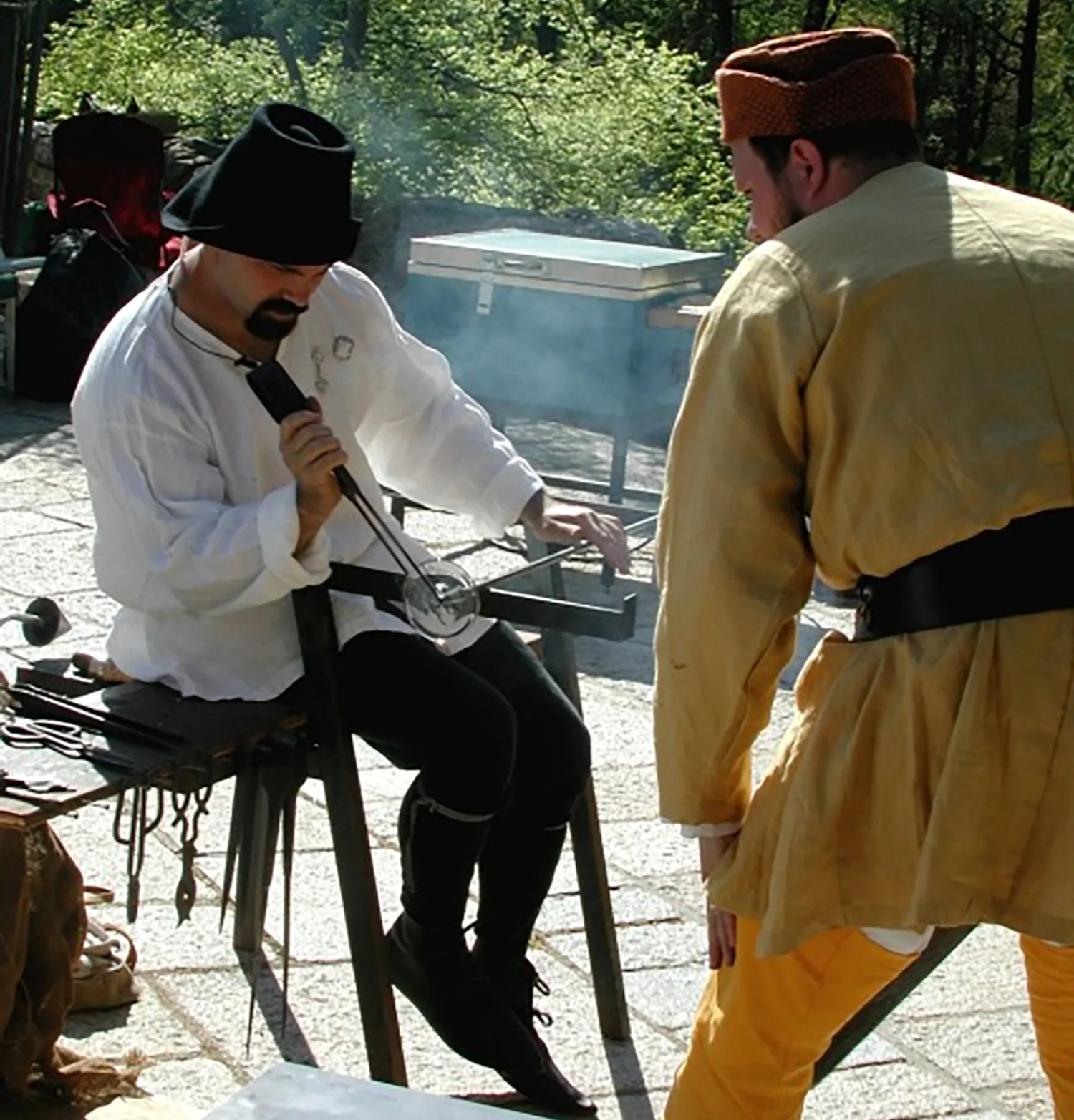 Figure 10: Jason Klein of Historical Glassworks at the glassblower’s bench, using the jacks to create a rondel, a circular disk made by spinning out a gather of glass. Photograph taken in 2006.