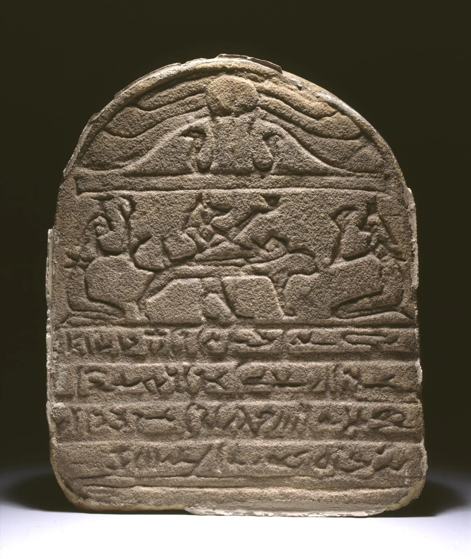 Figure 7: Anubis . This god is often shown attending to the mummified deceased. Individuals may have wanted amulets of Anubis to offer protection to their mummified remains (see Figure 6). A funerary stela from the site of Dendereh shows Anubis attending to the mummy of the deceased; Isis and Nephthys flank either side of the funerary bier. Image courtesy of Penn Museum, E2983.