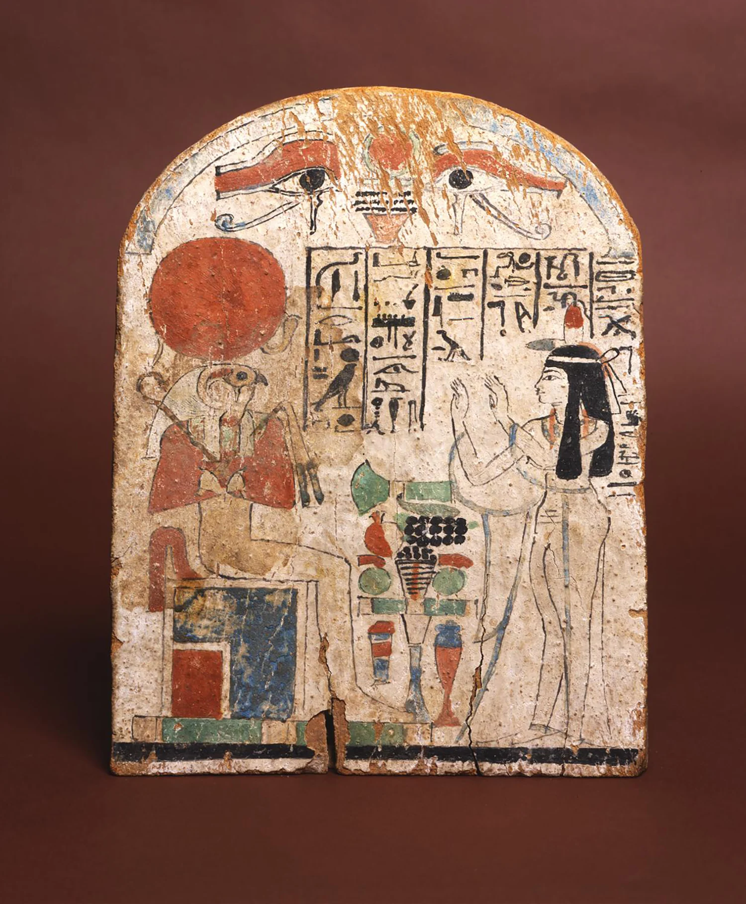 Figure 12: Re-Horakhty . Tasheryt, the Chantress of Amun, worships the god Re-Horakhty (see Figure 11) on this painted wooden stela. The god is identified by name in the hieroglyphic inscription. Image courtesy of Penn Museum, E2043.