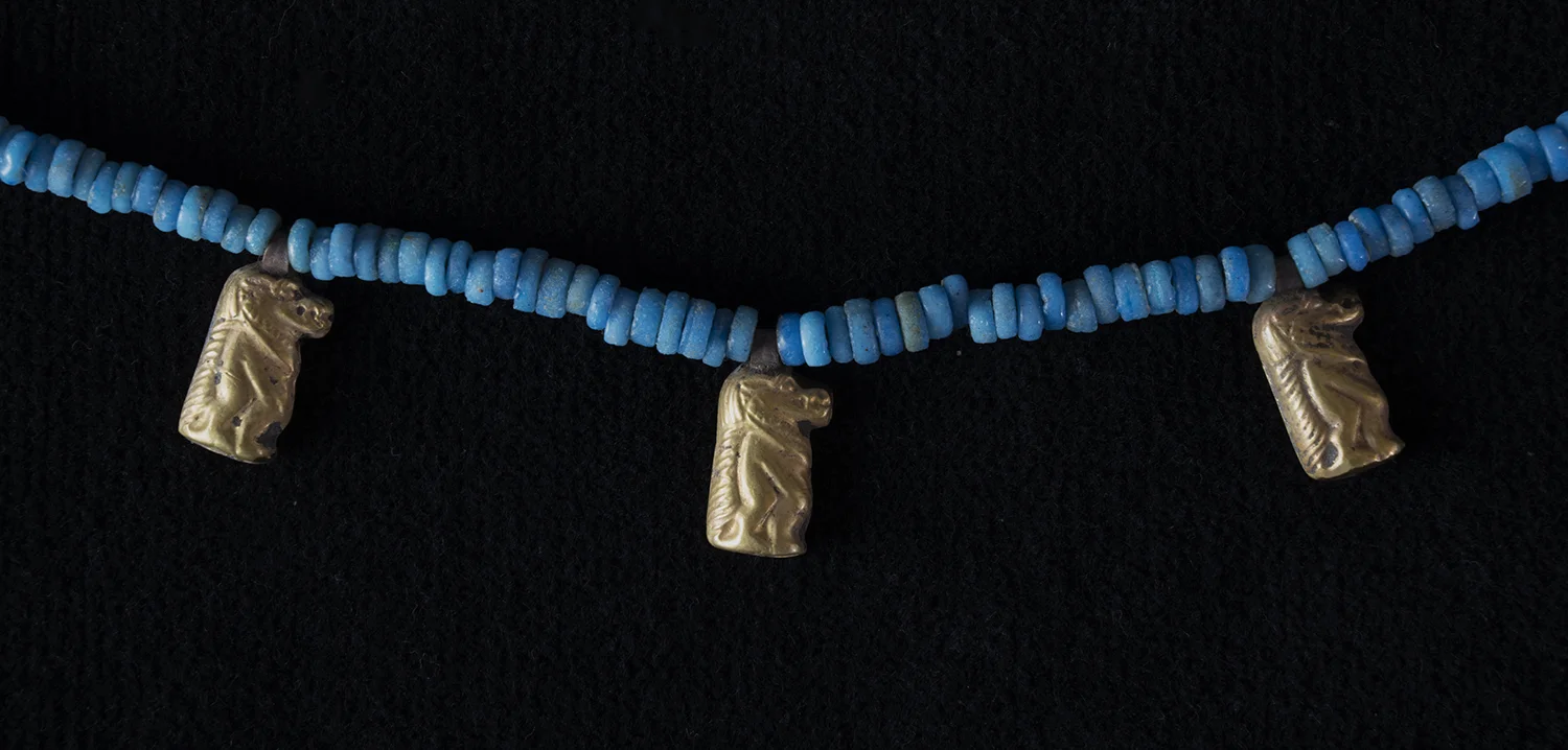 Figure 14: Taweret . Pregnant and nursing women used amulets of Taweret to protect themselves and their babies from evil spirits. Like Bes, this goddess is fearsome in appearance, combining the physical attributes of the hippopotamus, crocodile, and lion. Glencairn has a number of beaded necklaces which incorporate Taweret amulets, including this one with fifteen gold amulets showing the goddess in profile. Glencairn Museum 15.JW.573. (For more on Taweret at Glencairn, see The Goddess Taweret: Protector of Mothers and Children No. 9, 2014.)