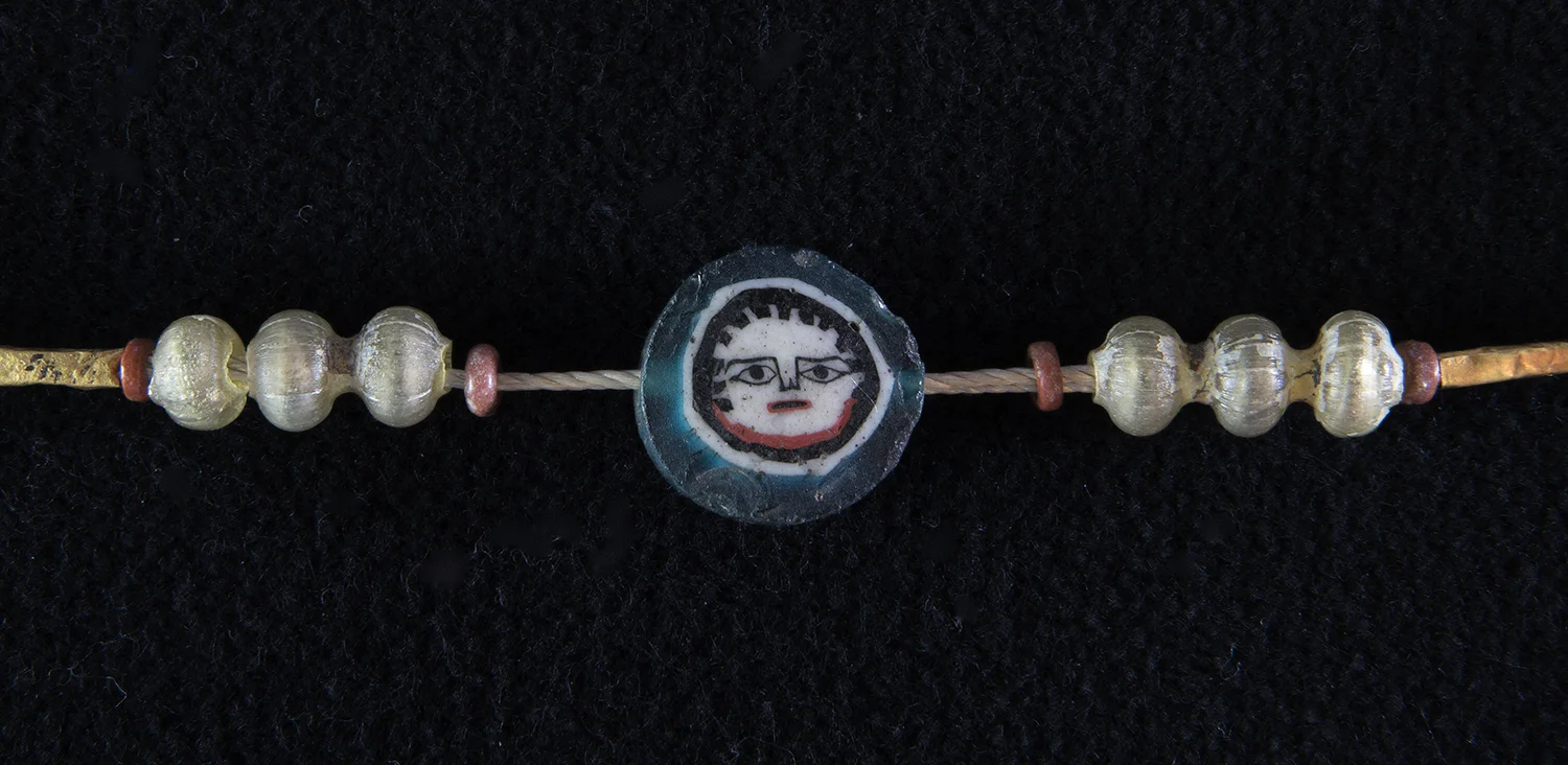 Figure 40: This glass mosaic bead (Glencairn 15.JW.77) features a tiny, detailed face. Beads like these were made by flattening a sliced section of complex mosaic glass canes.