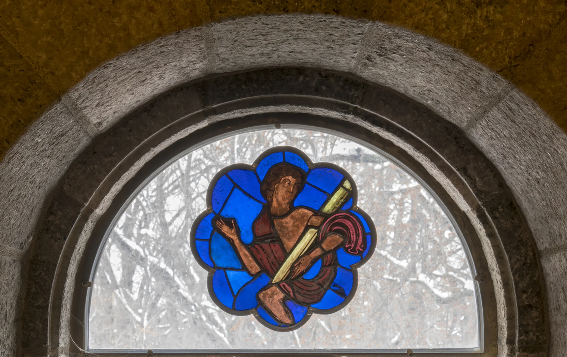 Figure 3: This rose window panel, from an abbey in northeastern France, depicts a male nude figure, half-clad in a shroud, rising from a sarcophagus (ca. 1215-1220, 03.SG.205). The panel is now installed in a clear-glass window on the third floor of Glencairn. 