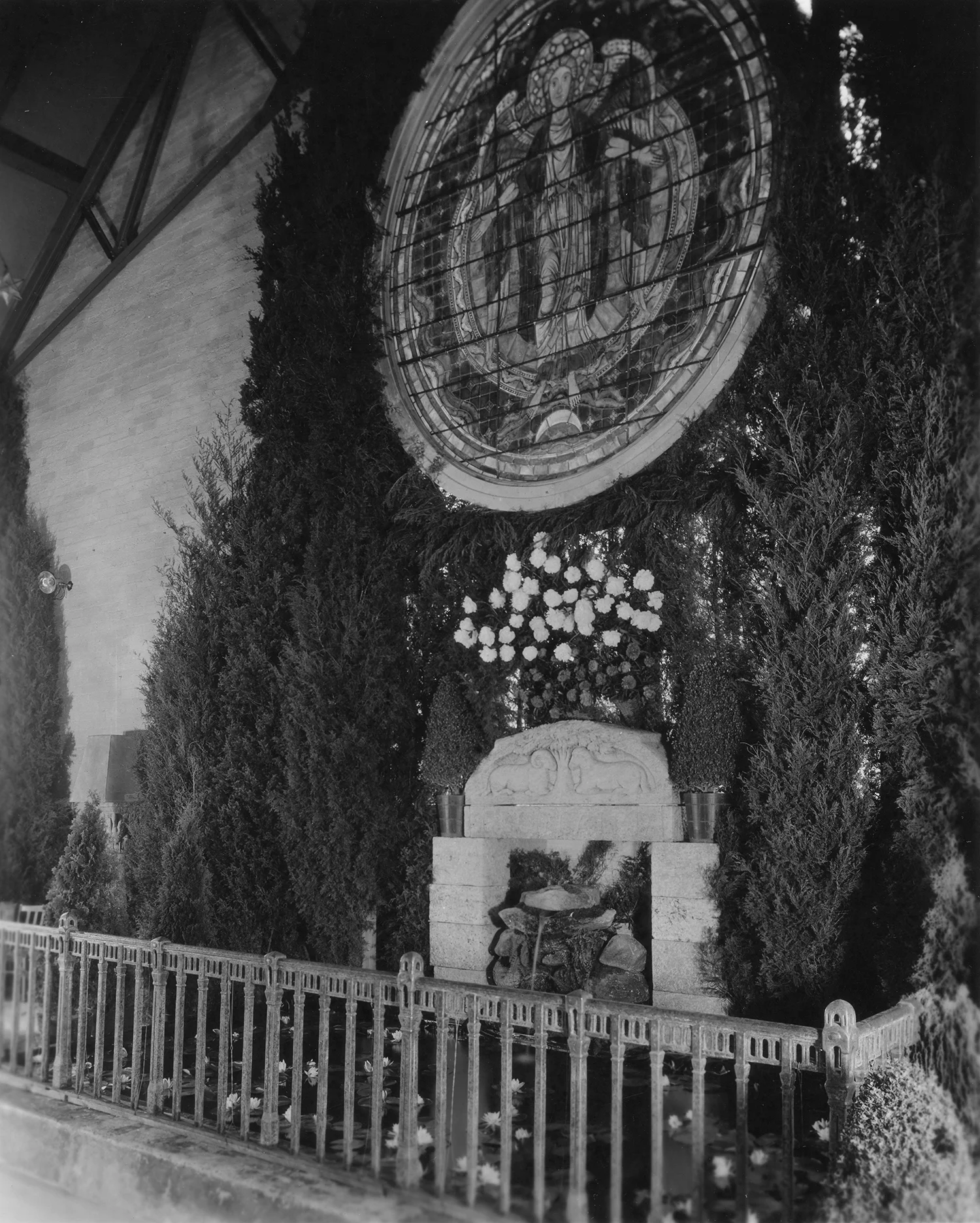 Figure 4: A stained glass window, a Monel metal railing, and the carved granite lintel for Glencairn's front door decorate one end of the Assembly Hall.