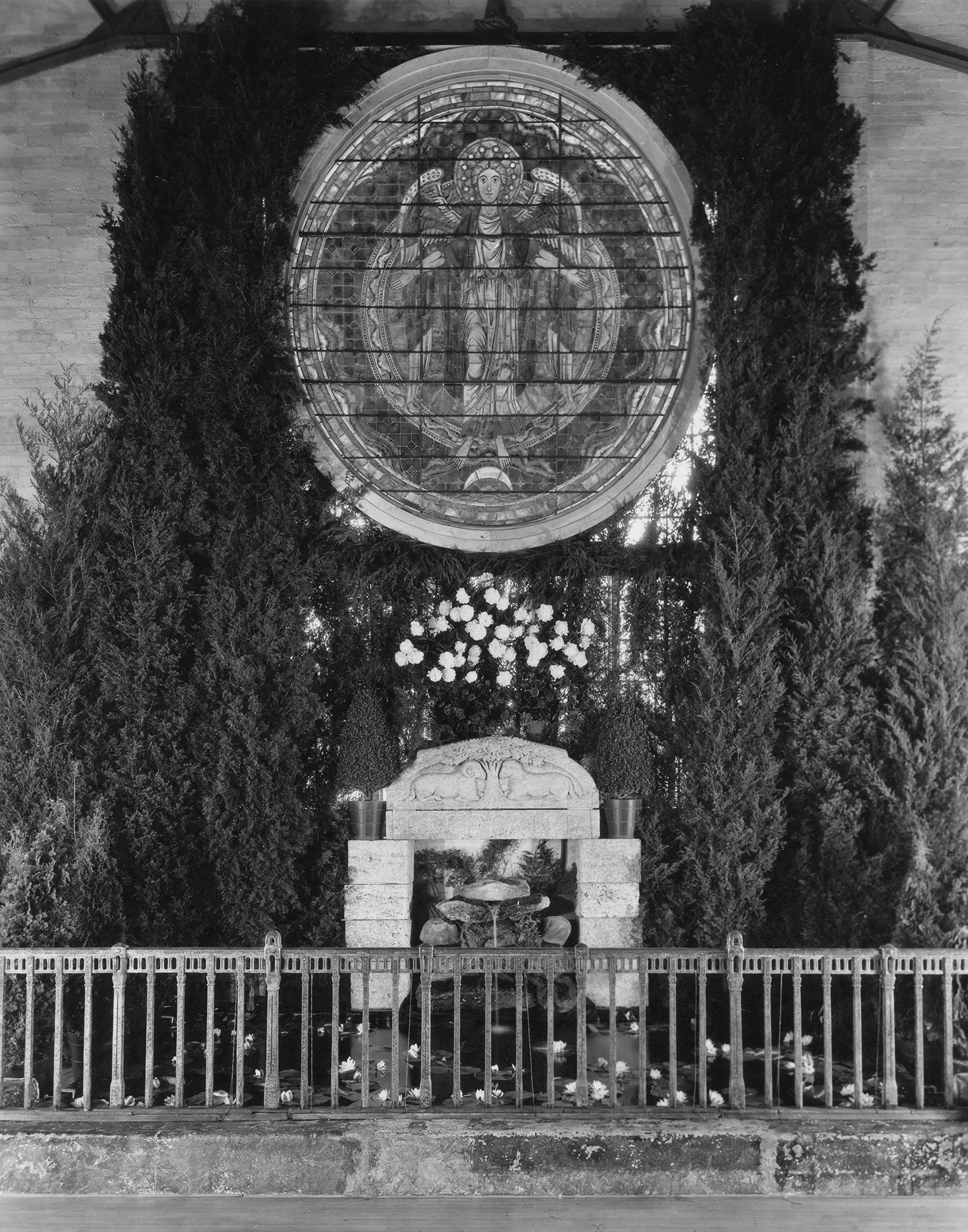Figure 17: The end of the Assembly Hall, opposite the stage. Decorations included a stained glass window depicting the Woman Clothed with the Sun, a Monel metal railing, and the lintel of Glencairn's front door.