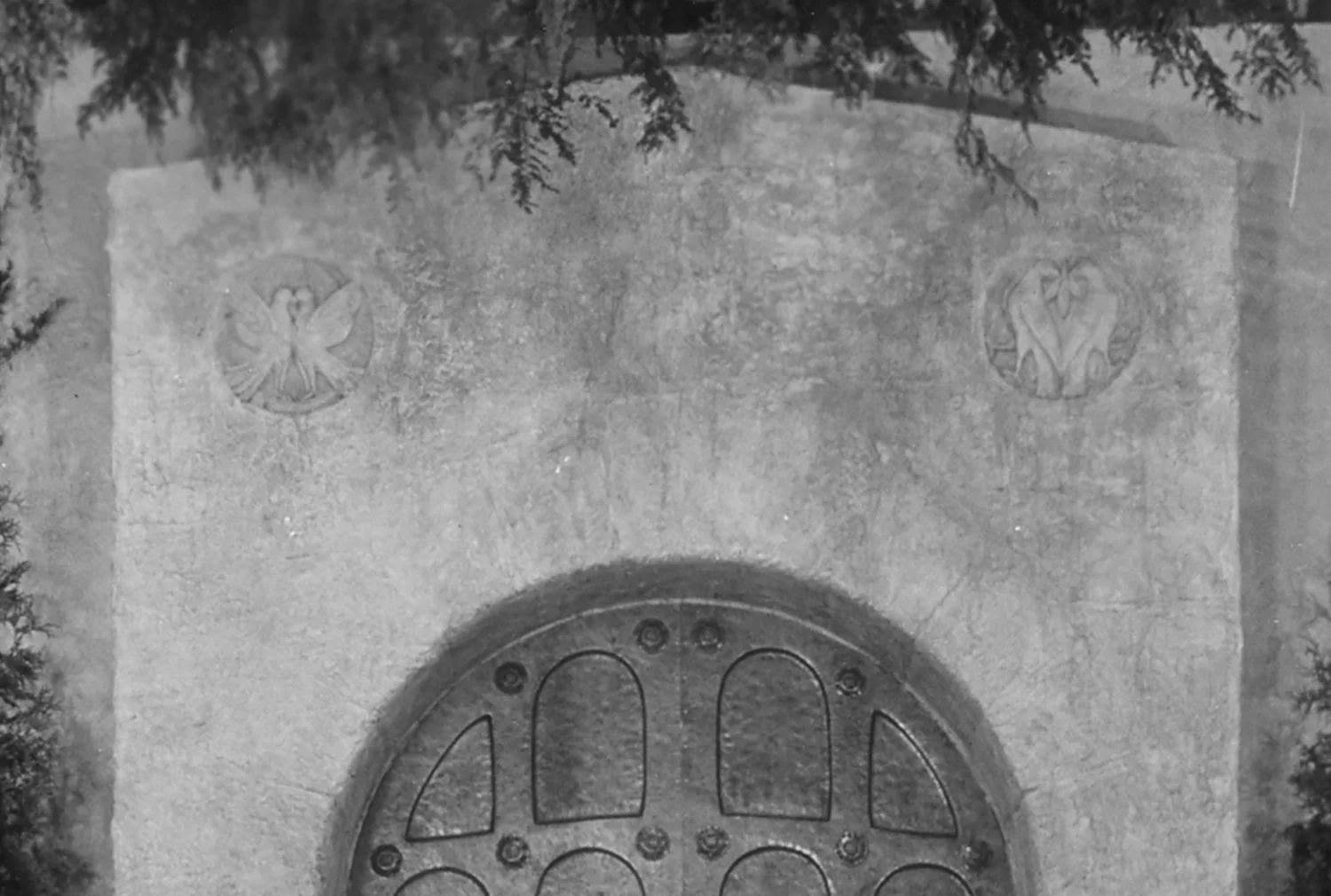 Figure 9: Two plaster medallions with doves can be seen above the bronze door on the Assembly Hall stage. They were never realized as finished designs in Glencairn.